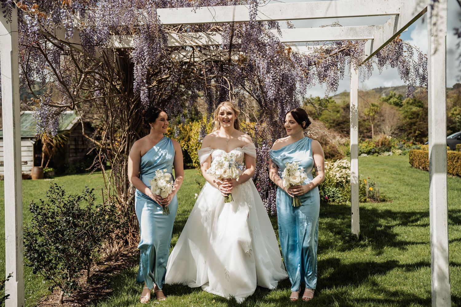 Wedding ceremony setup with white pergola and floral decorations in an outdoor garden setting.