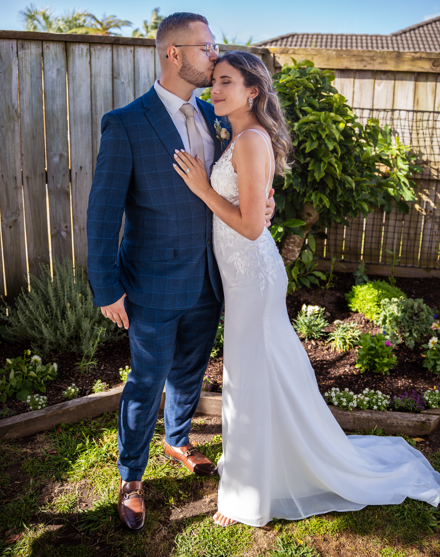 Newlyweds share an intimate moment in a garden setting with lush greenery.