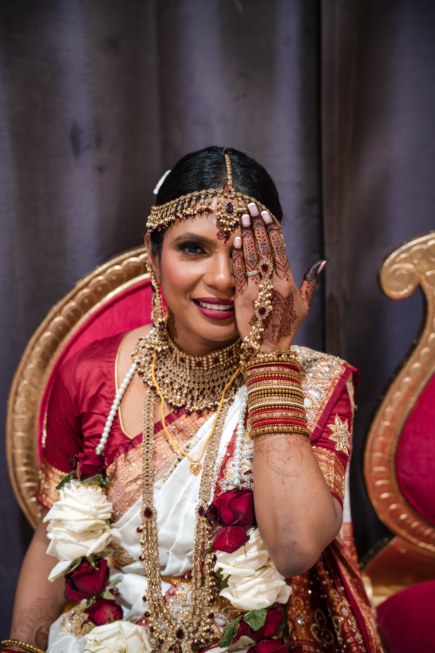 Traditional Indian bride in ornate gold jewelry and red and white sari.