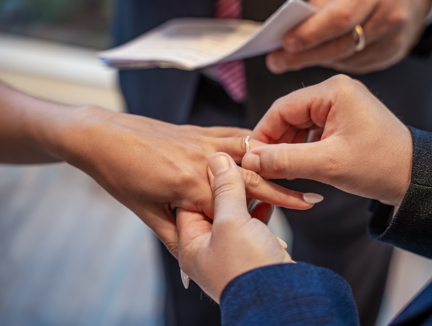 Close-up shot of hands exchanging wedding rings during a marriage ceremony.