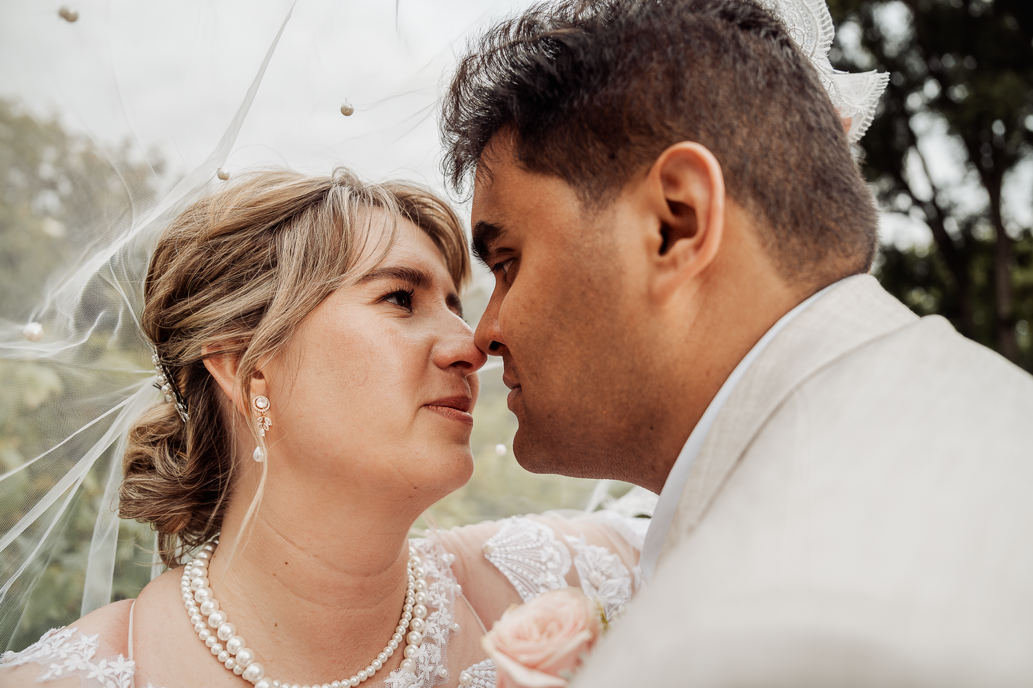 Intimate wedding portrait showing tender moment between newlyweds outdoors.
