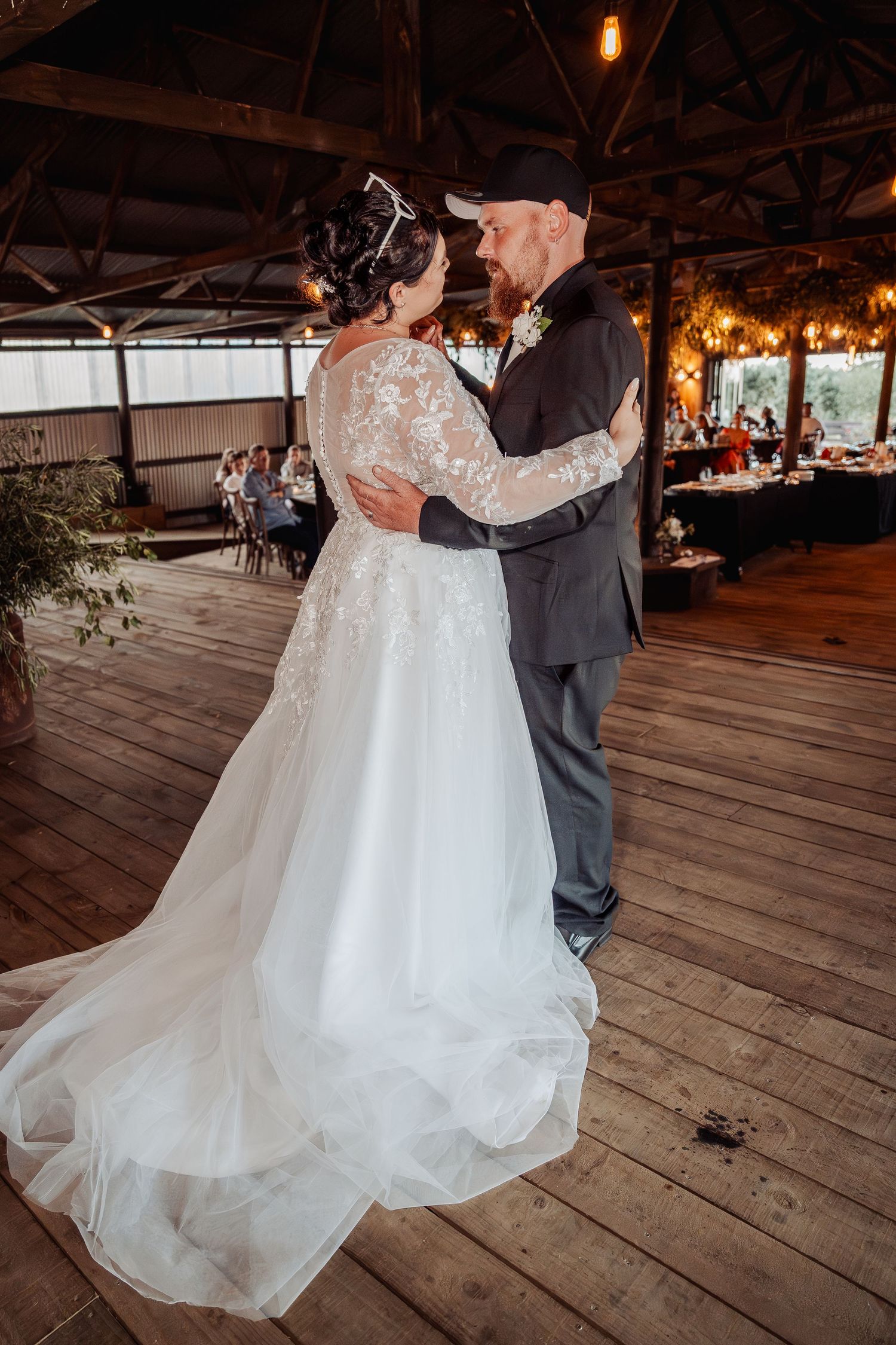 First dance moment in rustic barn venue with wooden floors and ambient lighting.