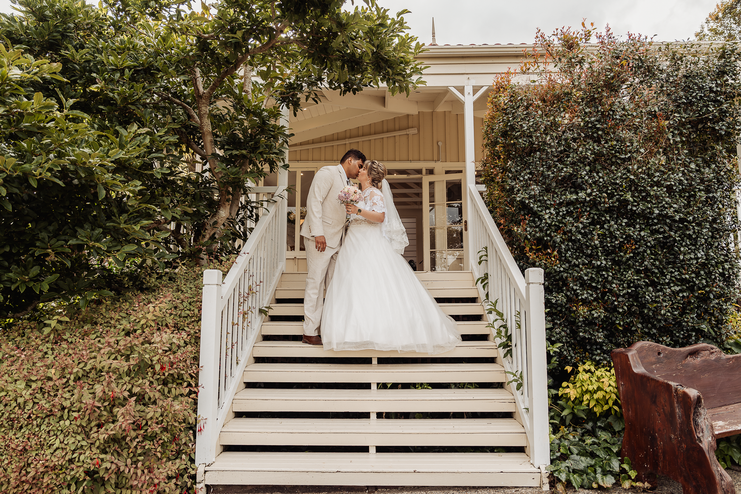 A white wedding dress photographed on a charming white wooden porch with stairs and railing.