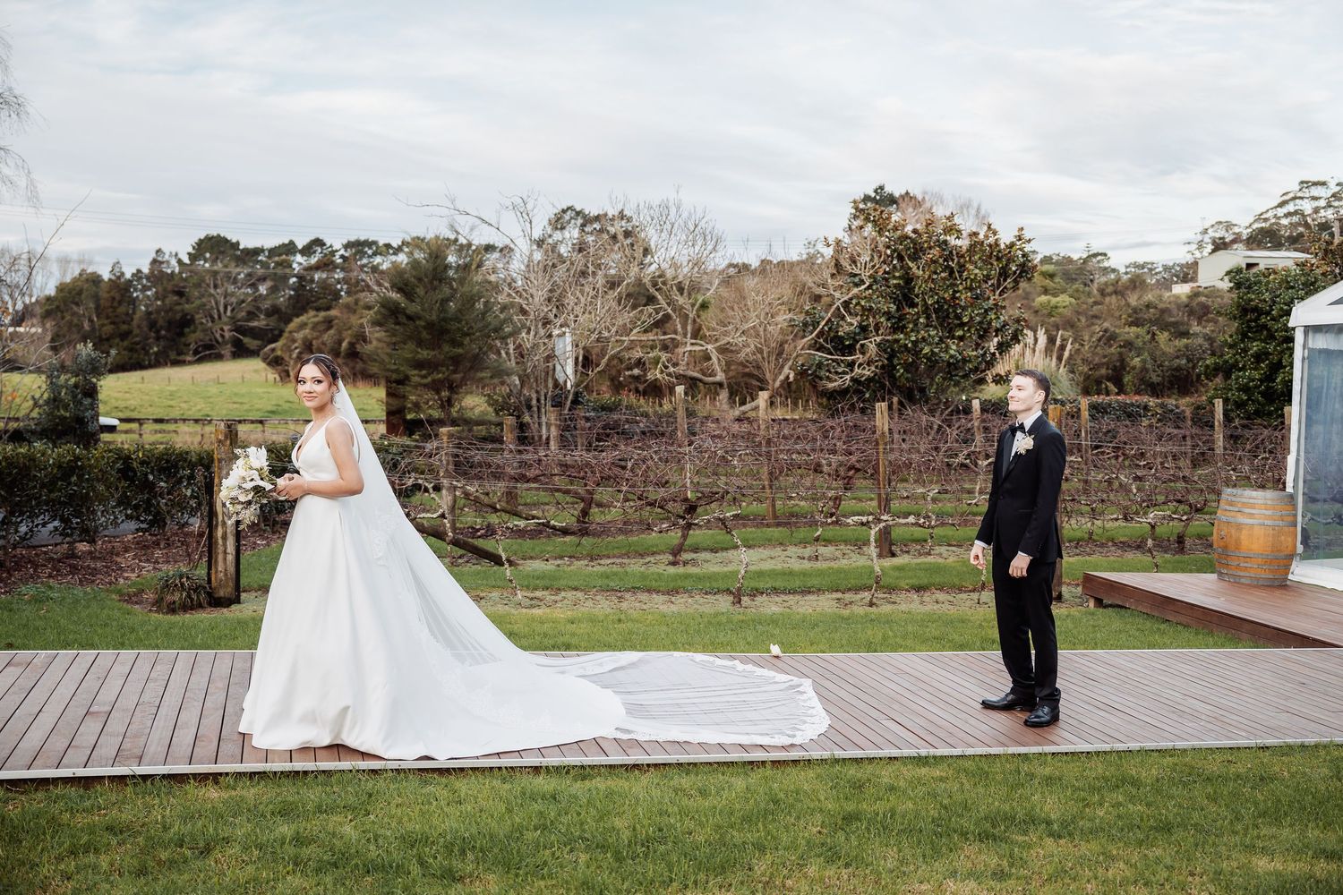 A couple takes wedding photos on a wooden deck with scenic garden views.