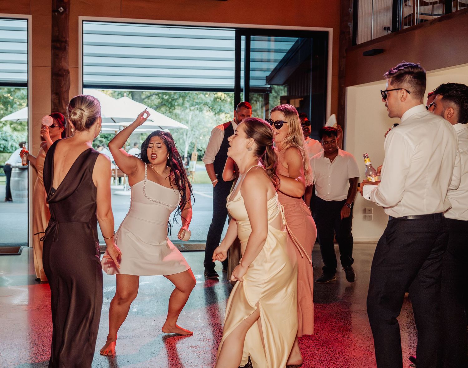 Wedding guests dance energetically on dance floor during lively outdoor reception celebration.