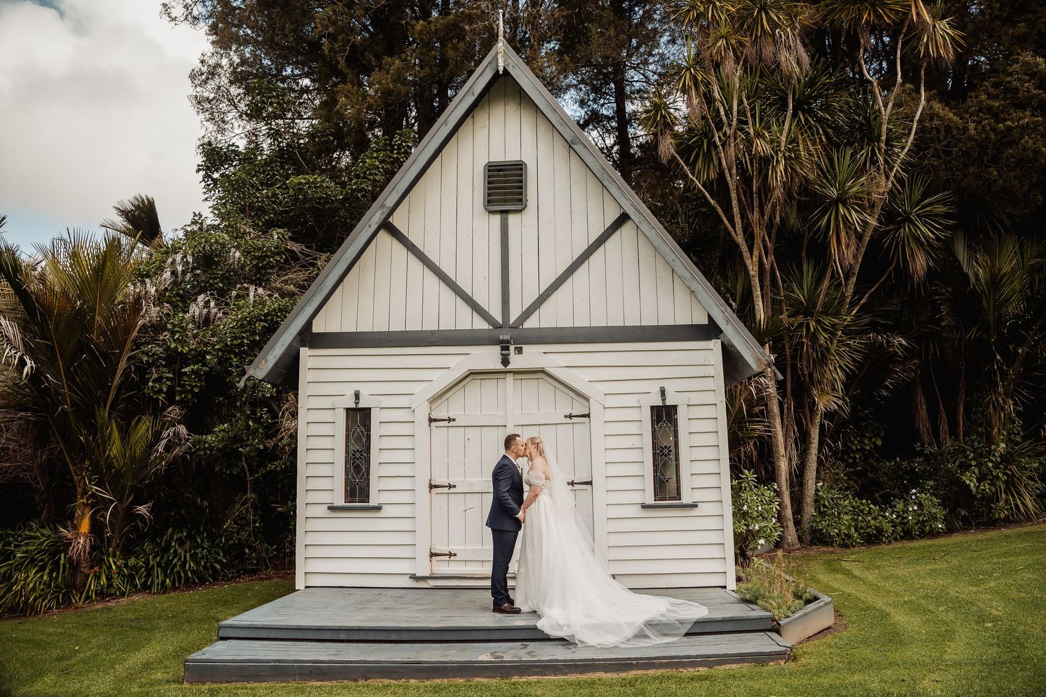 A charming white chapel wedding venue surrounded by palm trees and greenery.