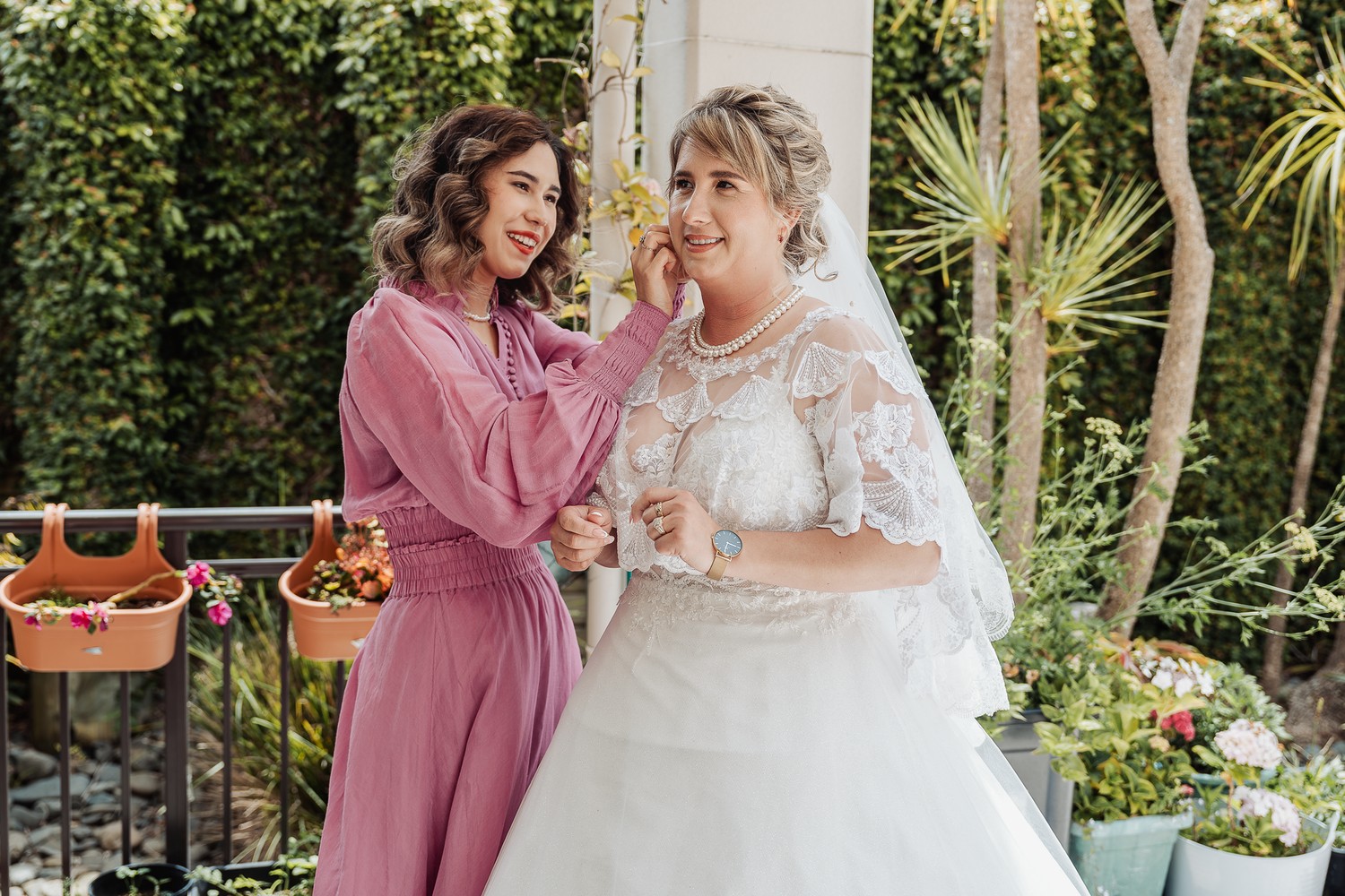 Two wedding party members share an emotional moment in a garden setting with floral decorations.