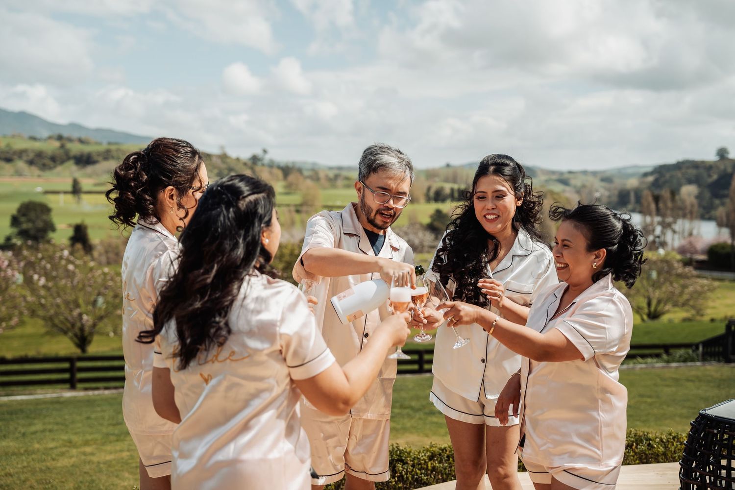 Friends share laughter and drinks while enjoying an outdoor gathering with mountain views in the background.