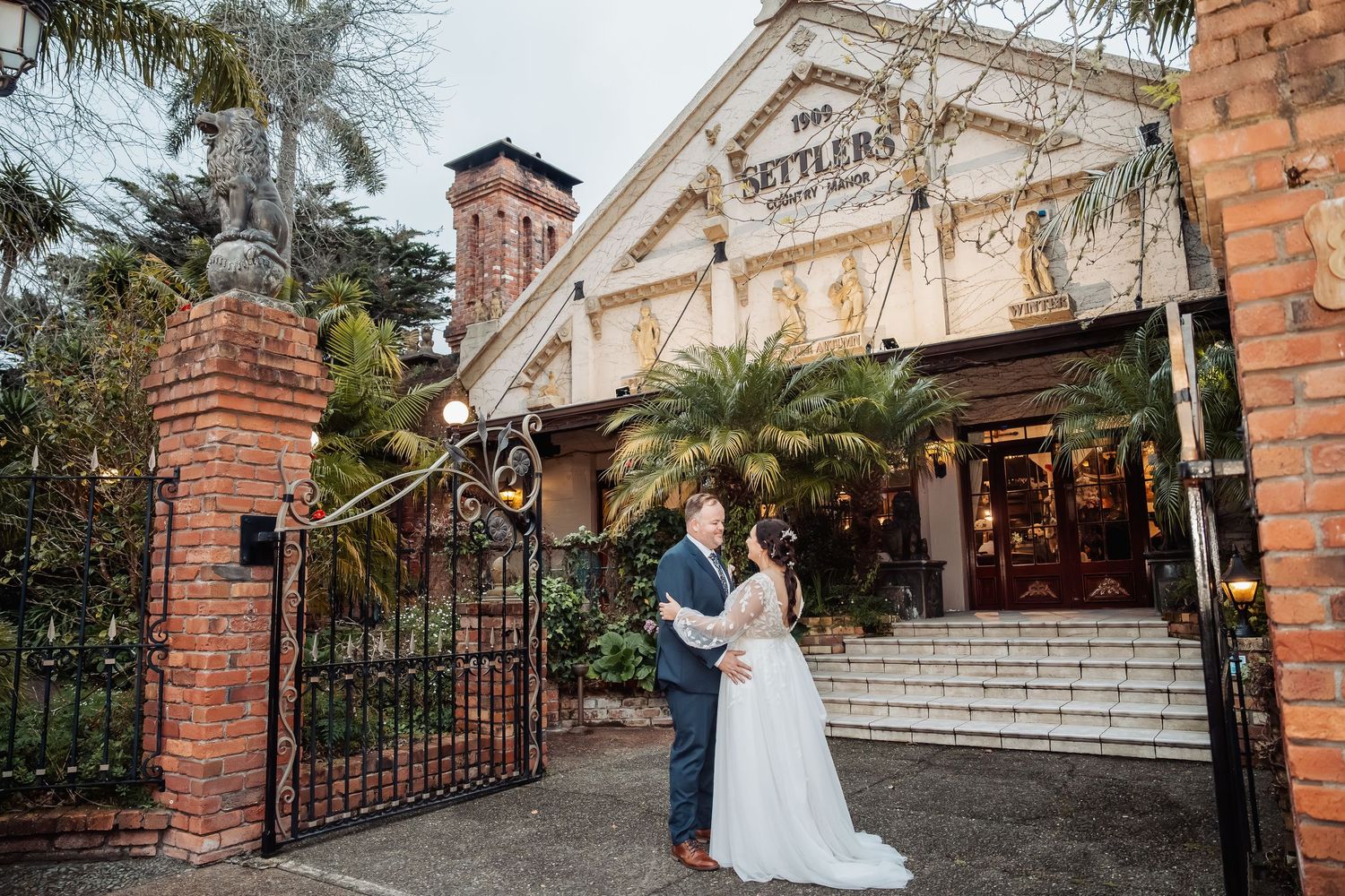Wedding venue exterior featuring brick walls and elegant white stone steps with palm trees.