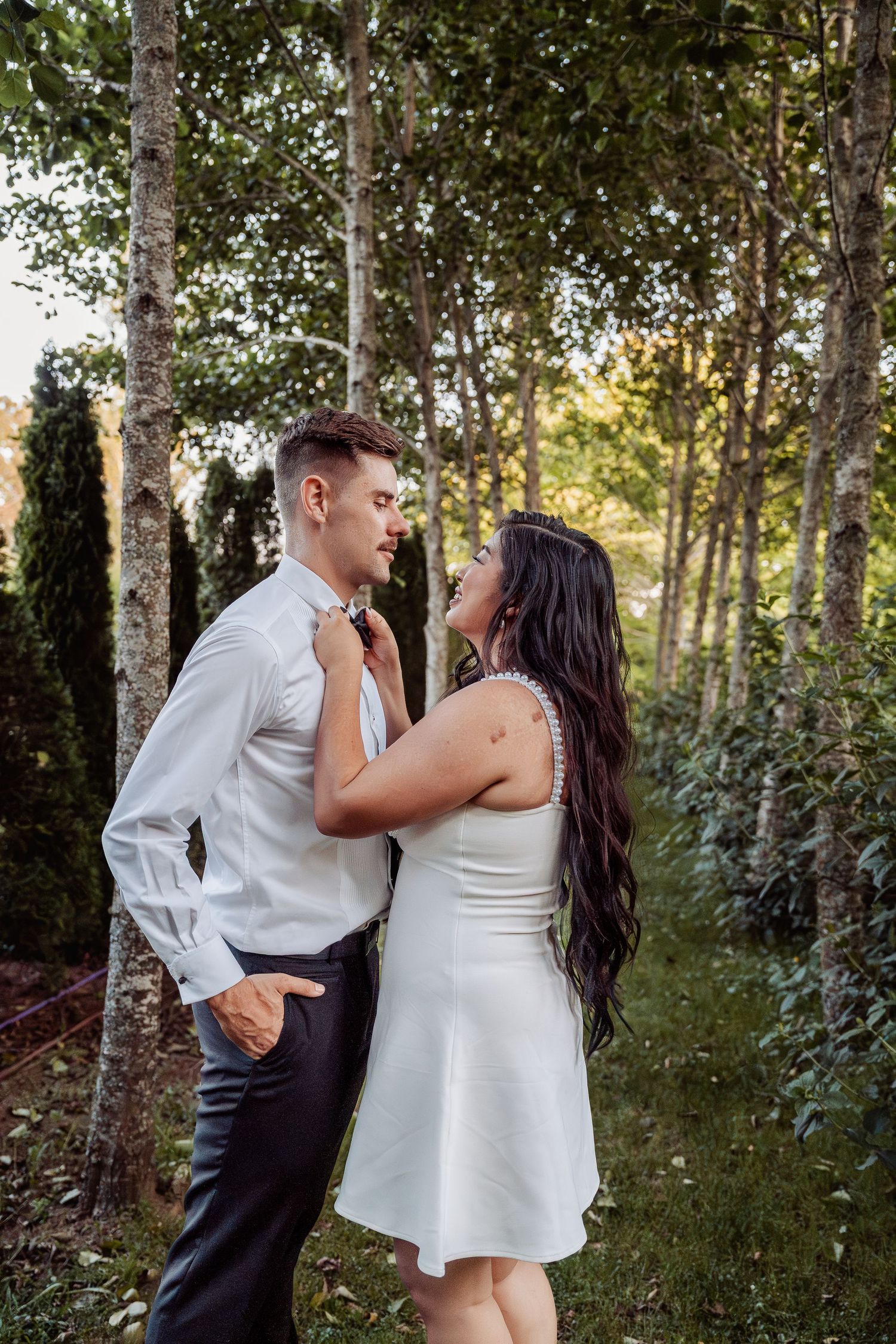 Bride and groom sharing intimate moment among birch trees in sunlit forest.