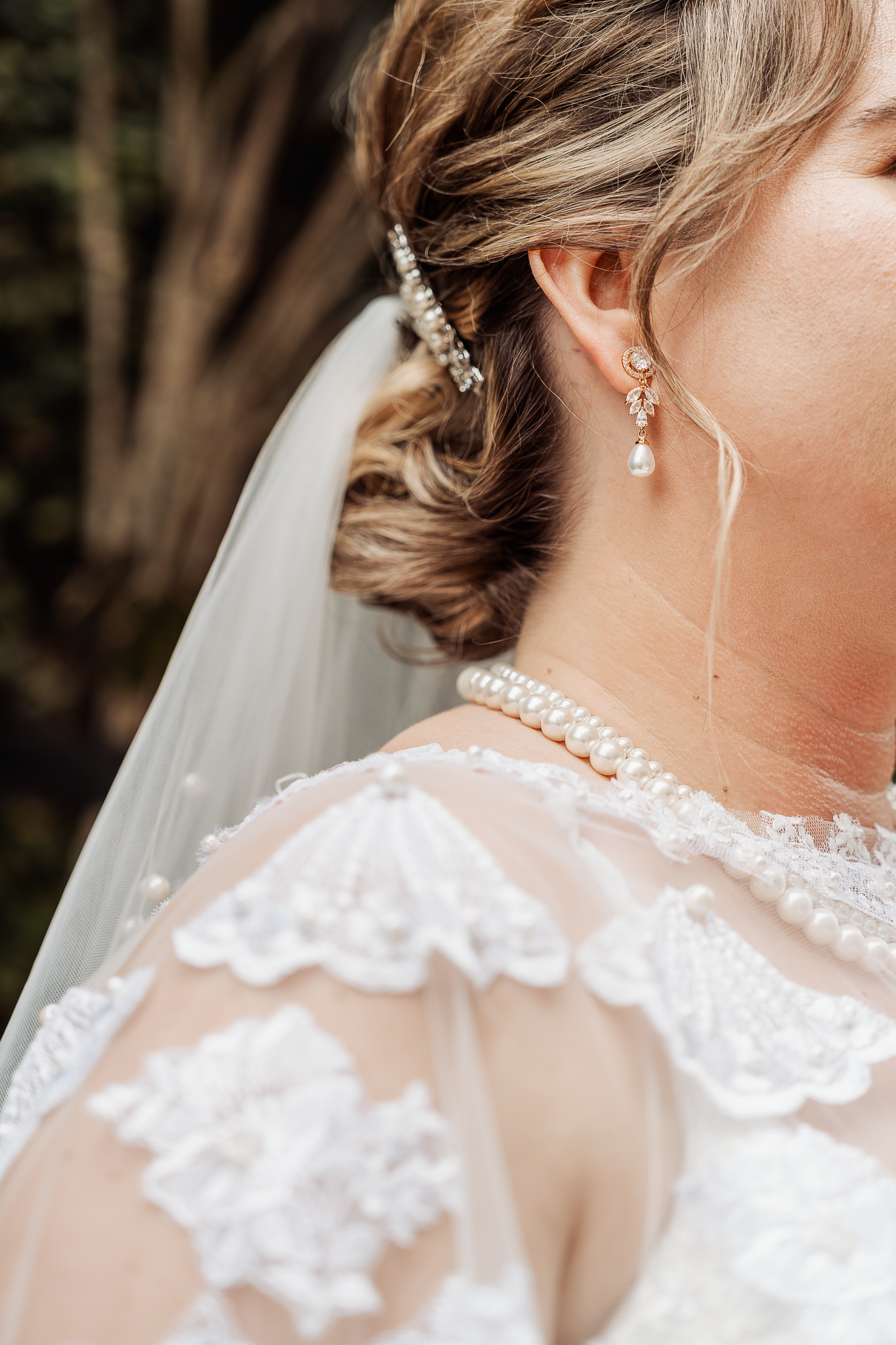 Close-up detail of bridal hair accessories, veil, and lace dress.
