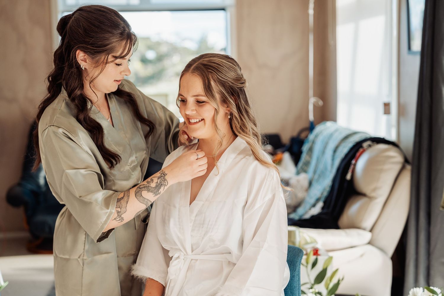 A beautician works on hair styling during bridal preparation in a cozy home setting.