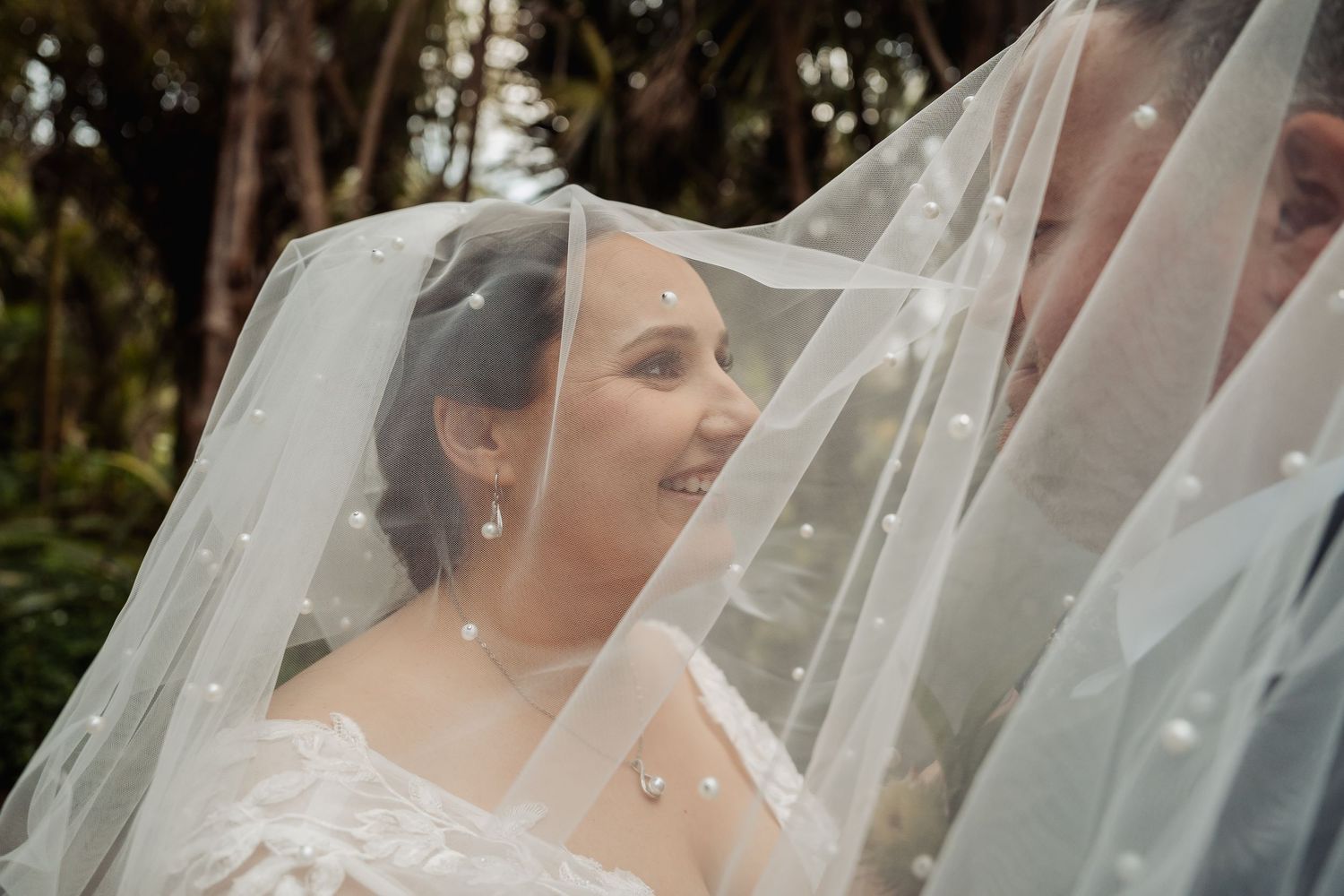 Delicate lace veil details captured in soft natural lighting during outdoor wedding photography.