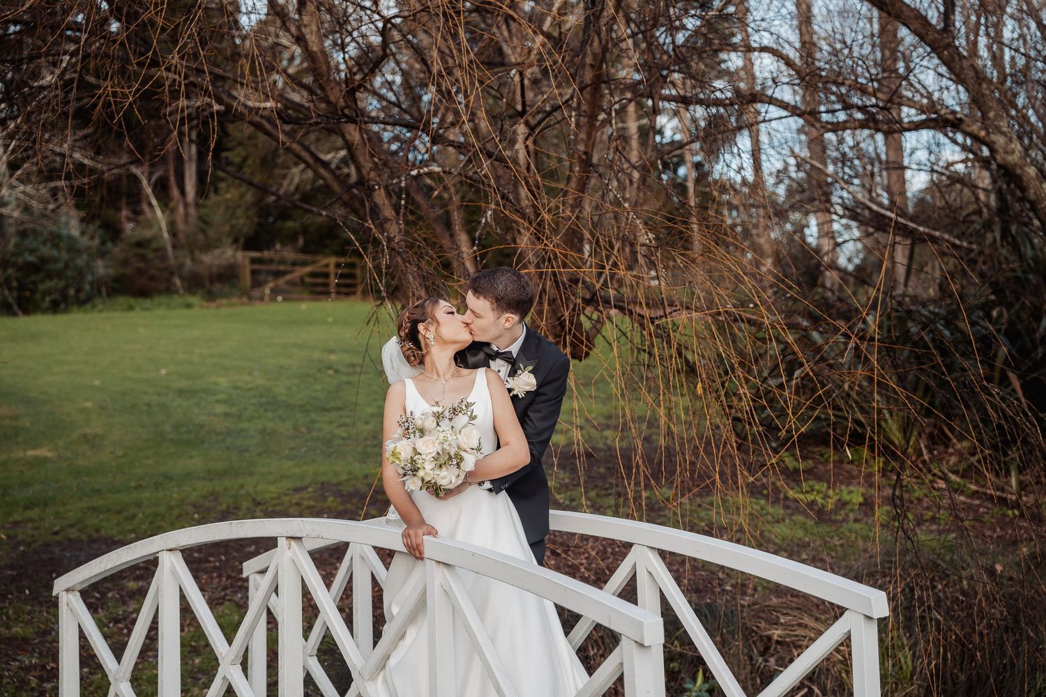 Elegant white gazebo with decorative railings in a romantic garden setting.
