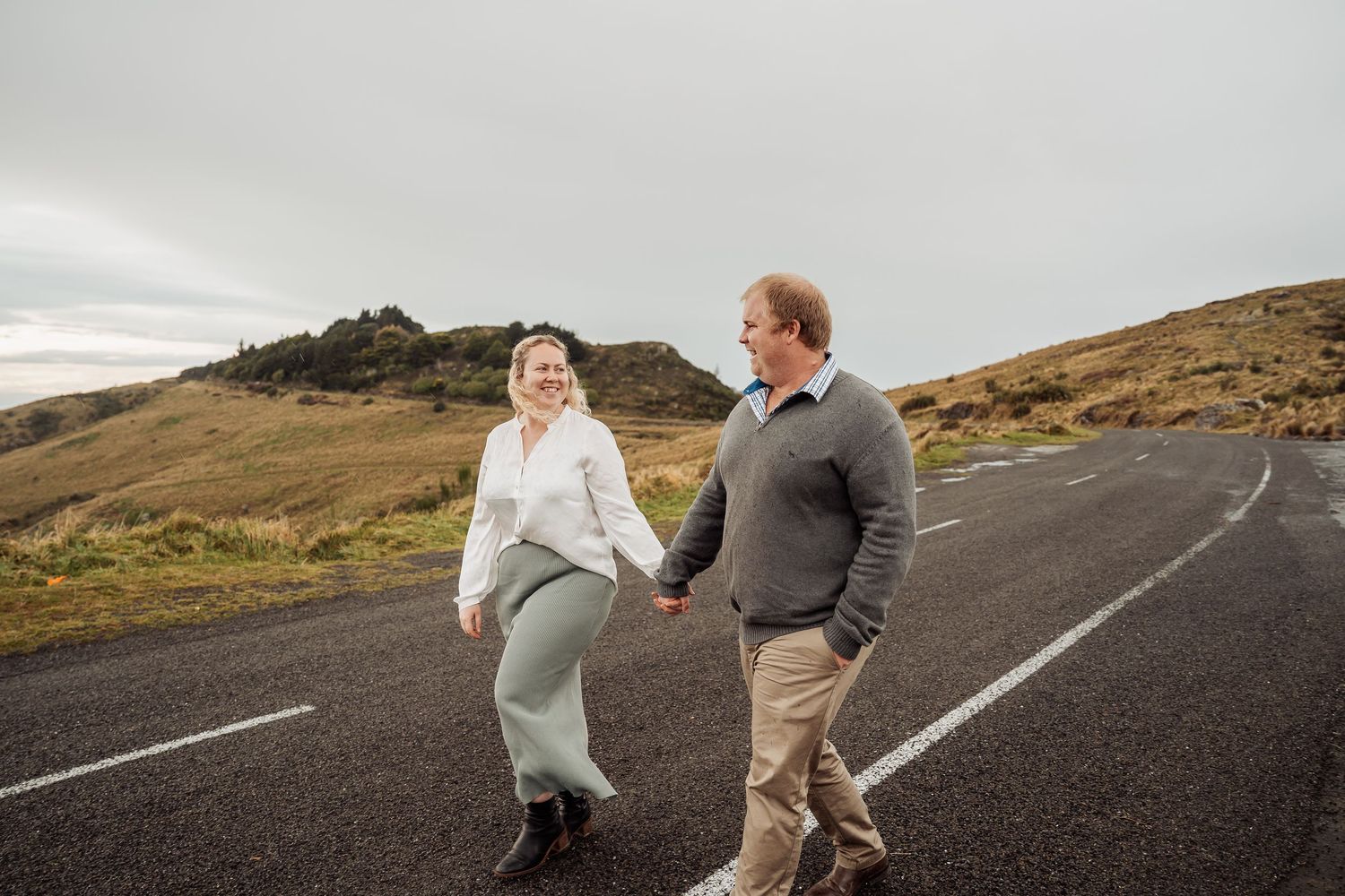 Scenic view of parent and child running together on a paved road through rolling hills on an overcast day.