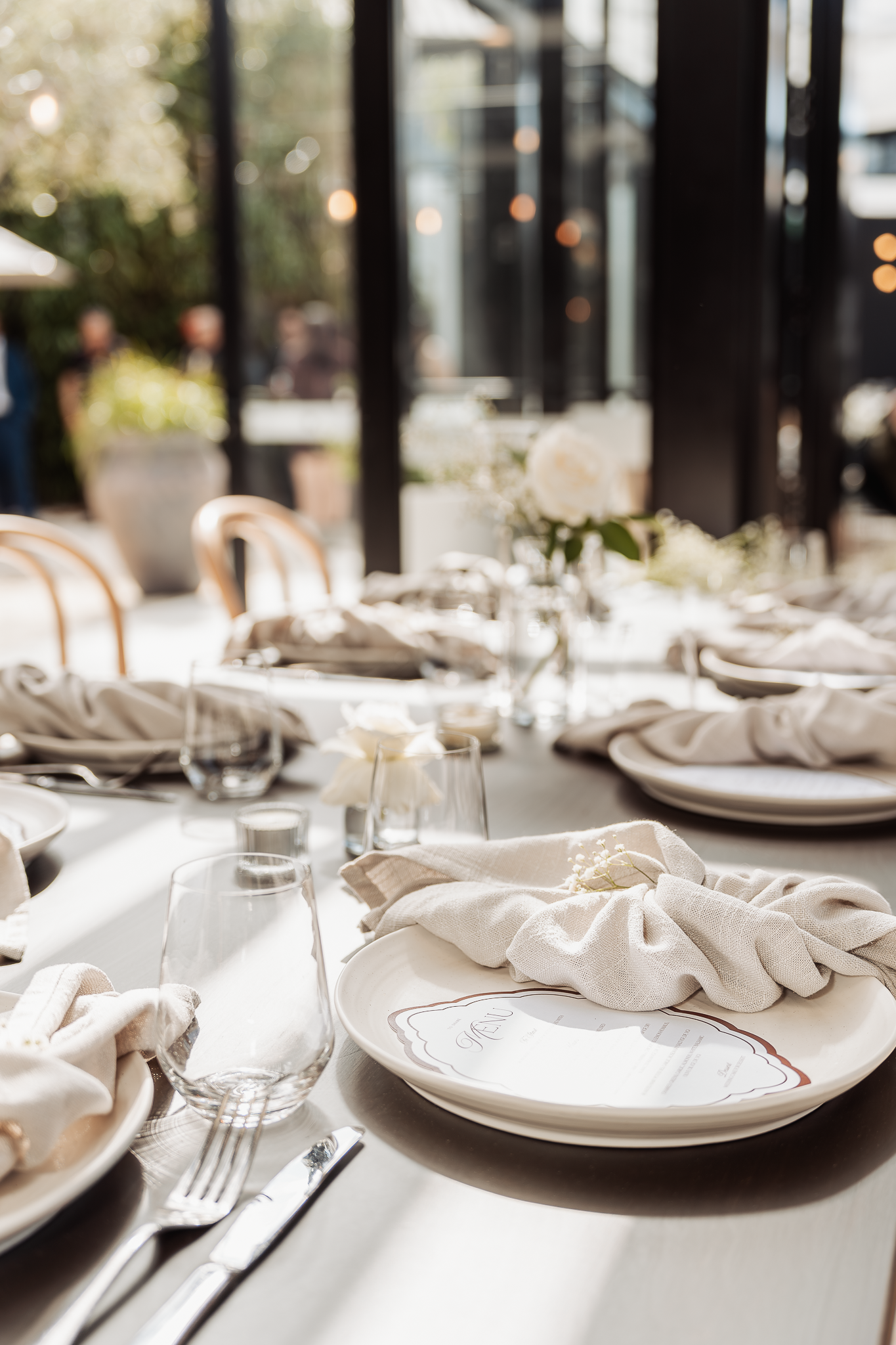 Elegant table setting with white linens and place settings at wedding reception.