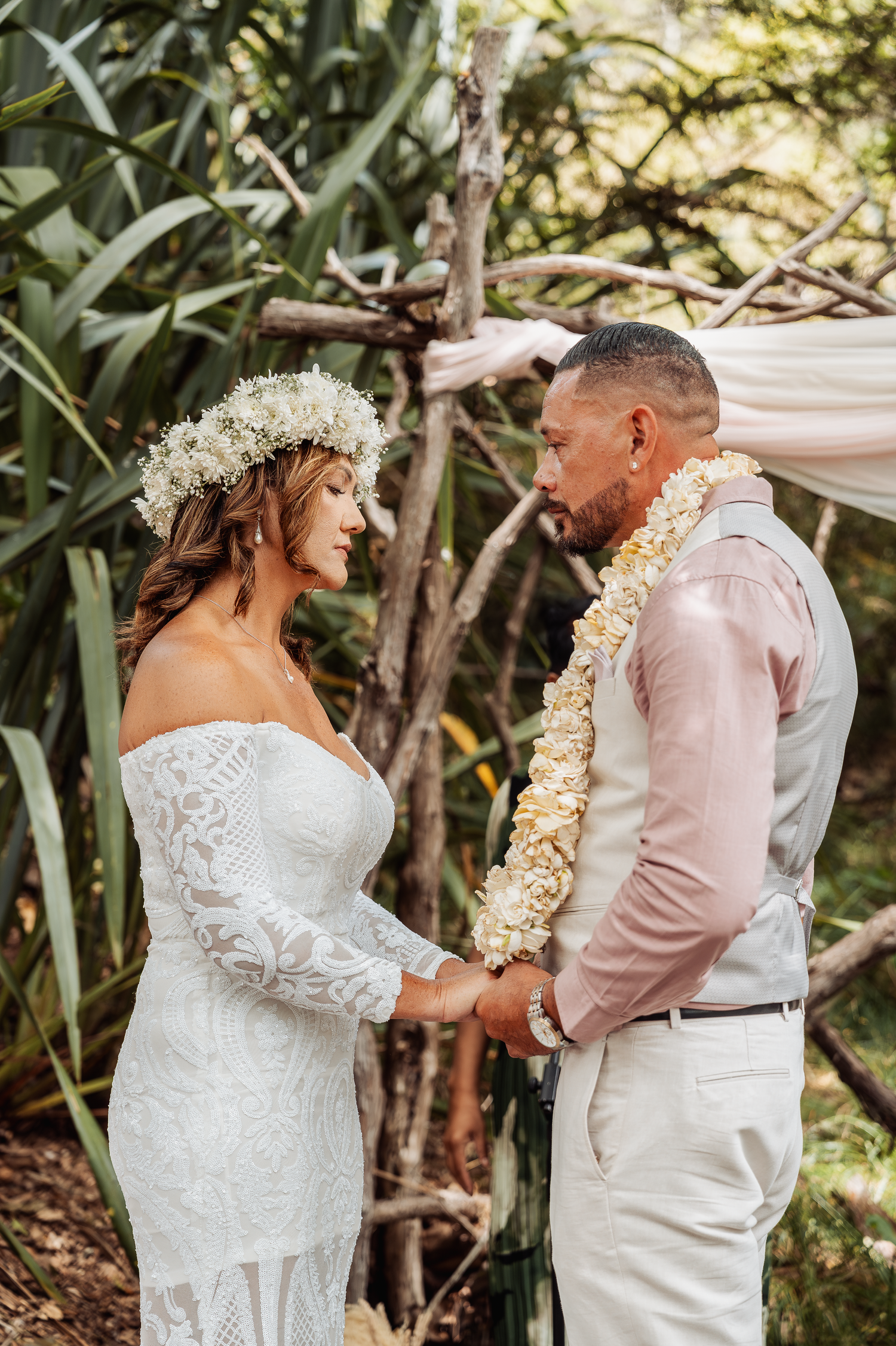 A couple shares a romantic moment during their tropical wedding ceremony with flower leis.