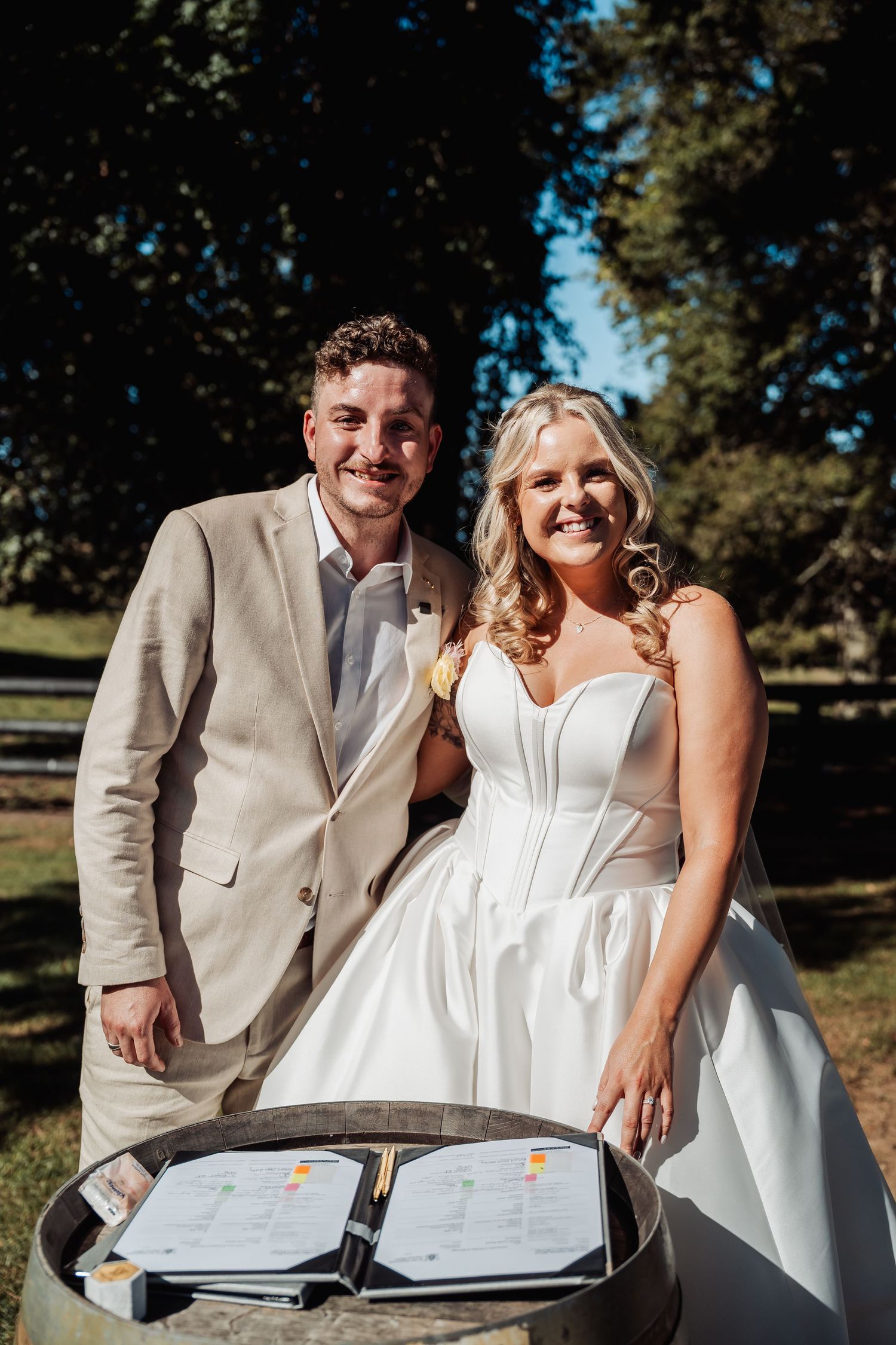 Smiling bride and groom posing together after signing their wedding certificate on a barrel.