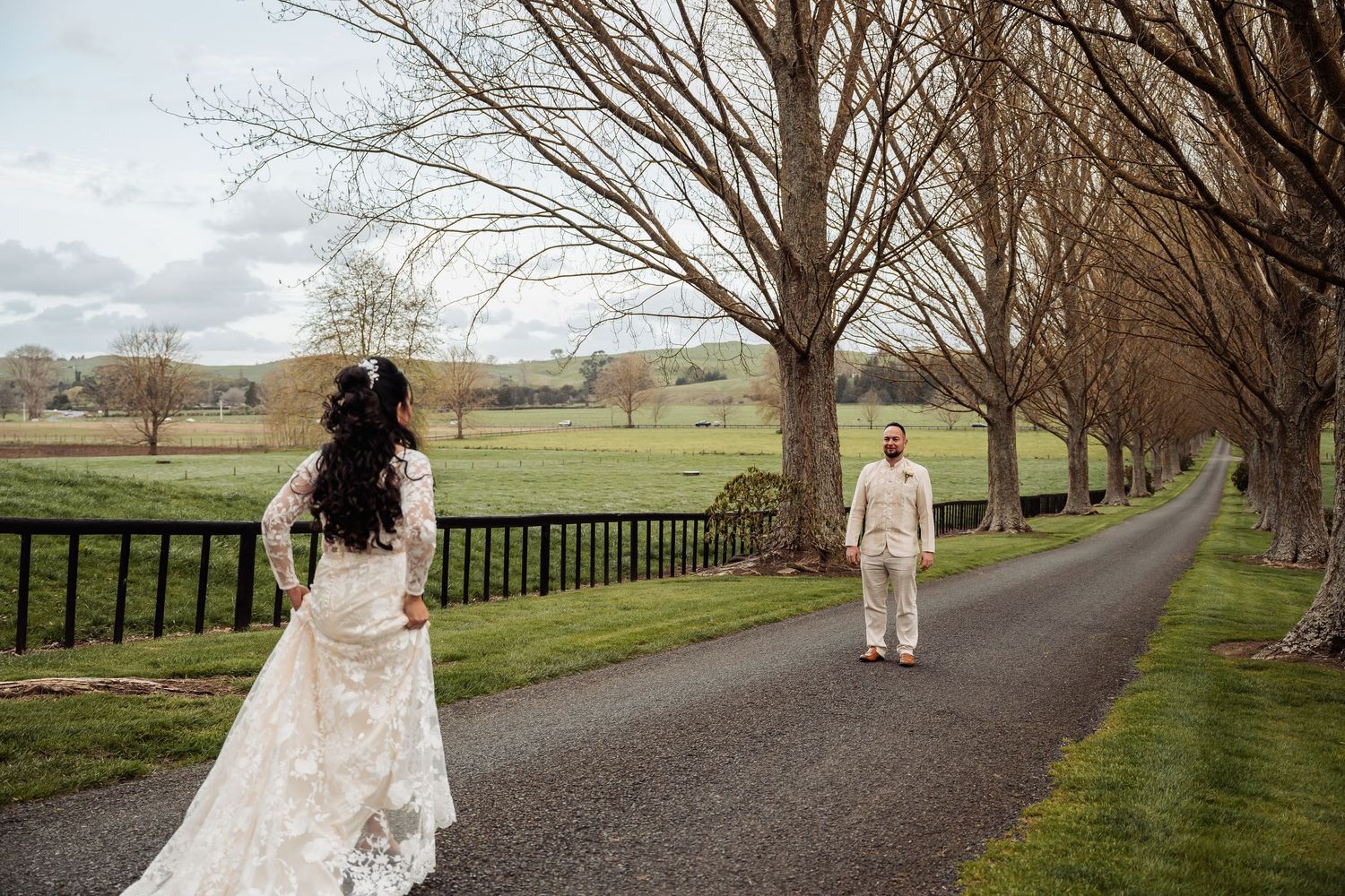 A romantic photo session along a fence-lined country road with bare winter trees.