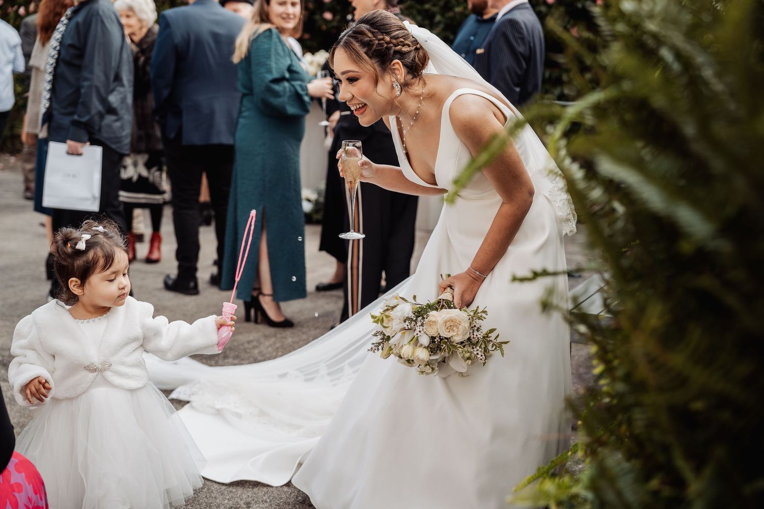 Wedding guests celebrate during an outdoor ceremony with a beautiful white gazebo and garden setting.