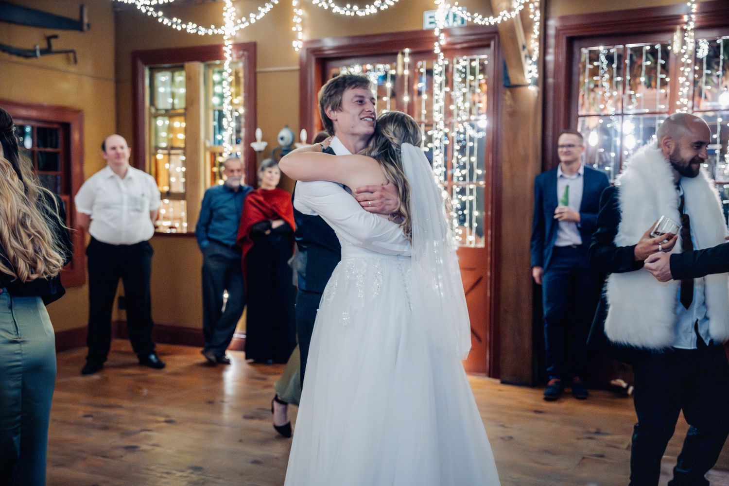 Couple shares romantic first dance under twinkling lights at wedding reception.