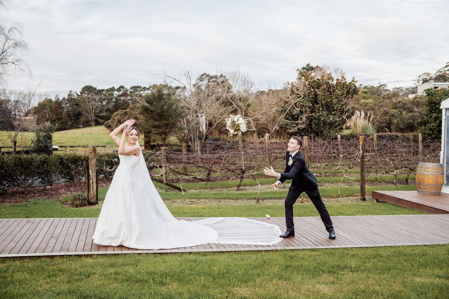 A scenic wedding photo session on rolling green hills with trees in the distance.