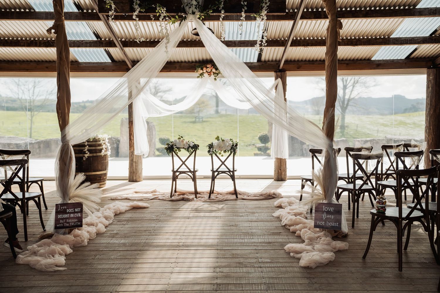 Rustic barn wedding venue with wooden beams and white drapes creating an elegant ceremony space.