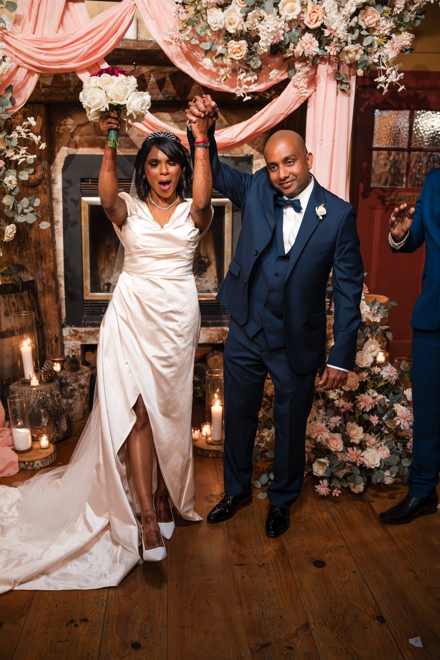 Celebratory wedding moment under a floral arch with pink draping.