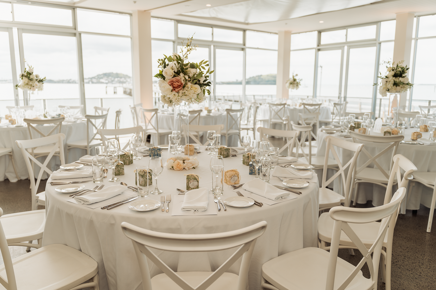 Elegant wedding reception venue with round tables decorated in white linens and floral centerpieces.