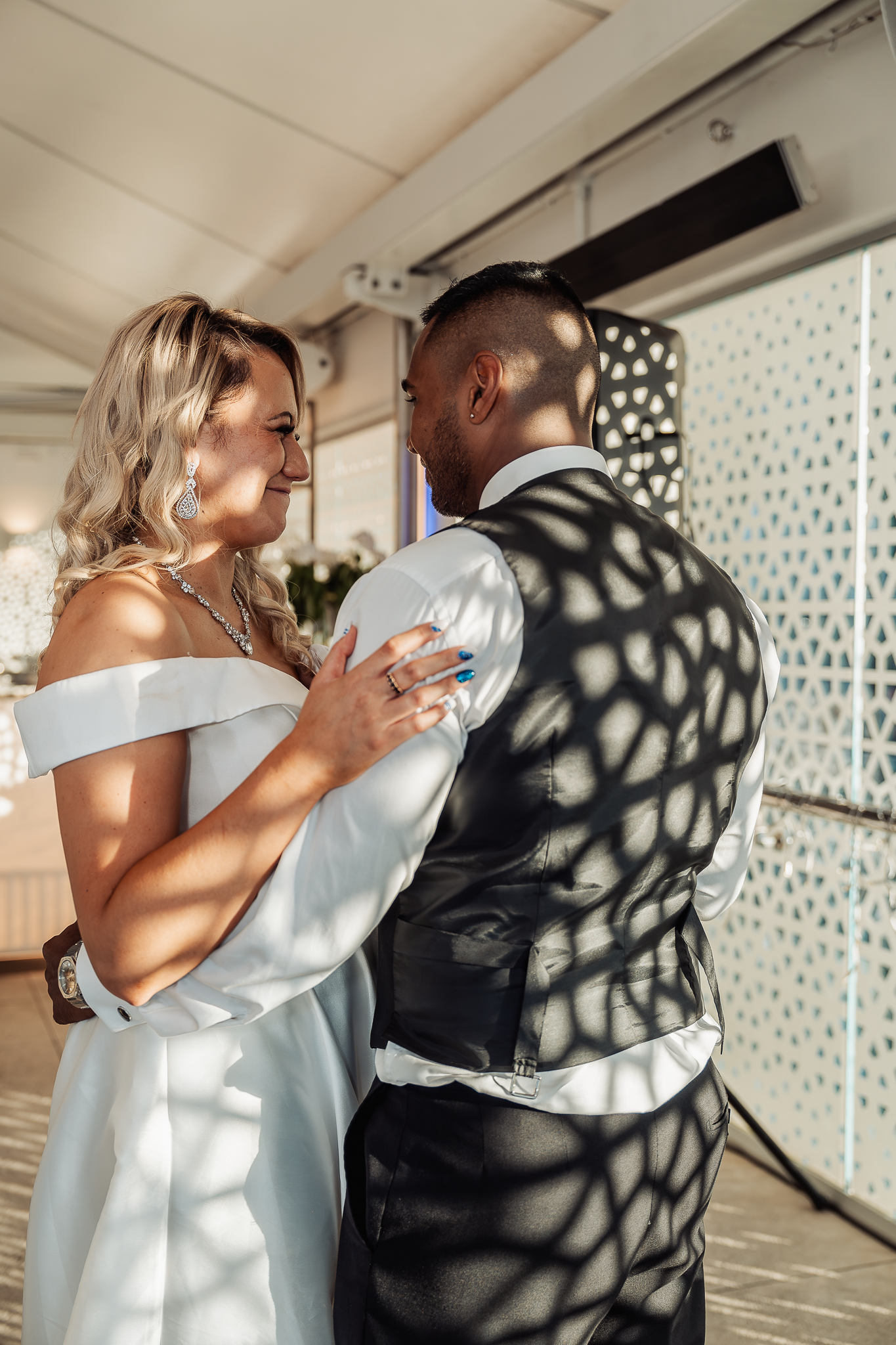 Couple shares intimate dance with dramatic lighting creating spotted shadows.