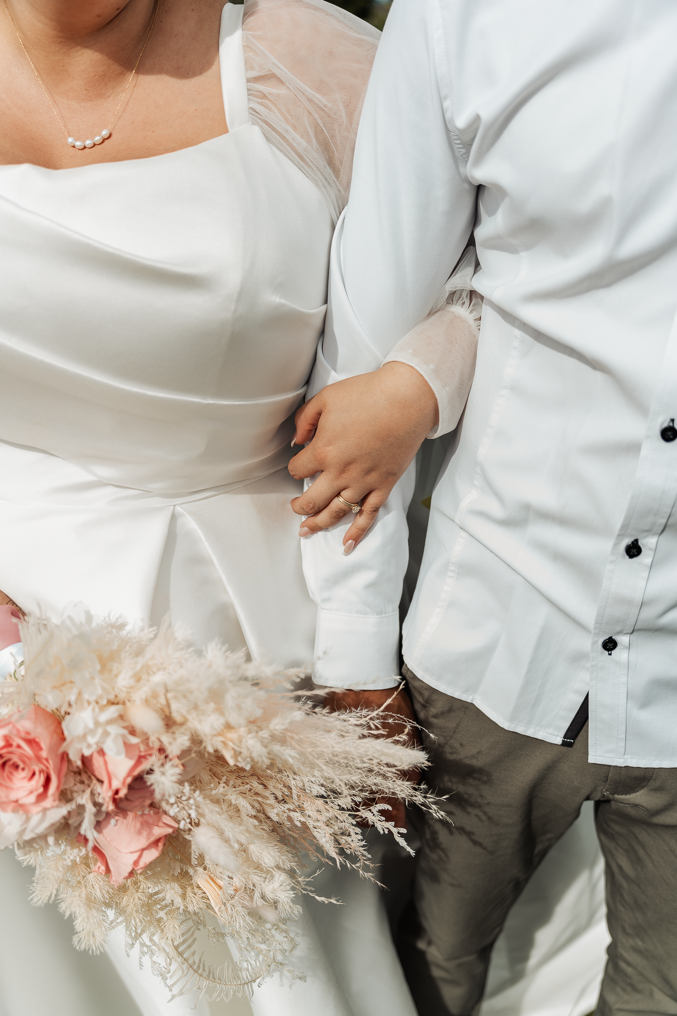 Detail shot of wedding attire with pink roses and pampas grass bouquet.