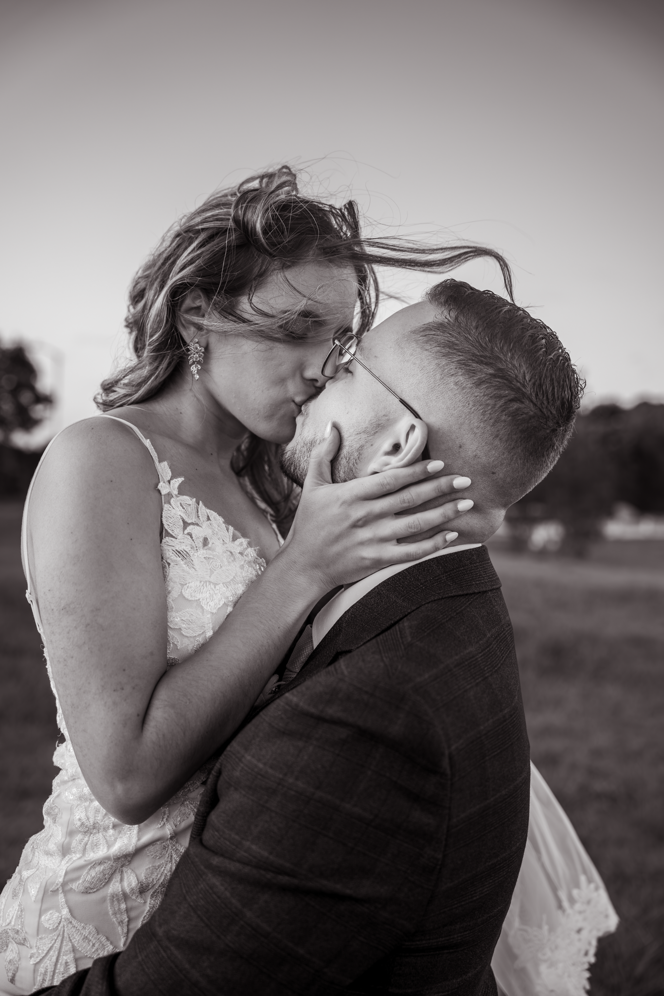 Black and white portrait of a couple sharing an intimate wedding day kiss.