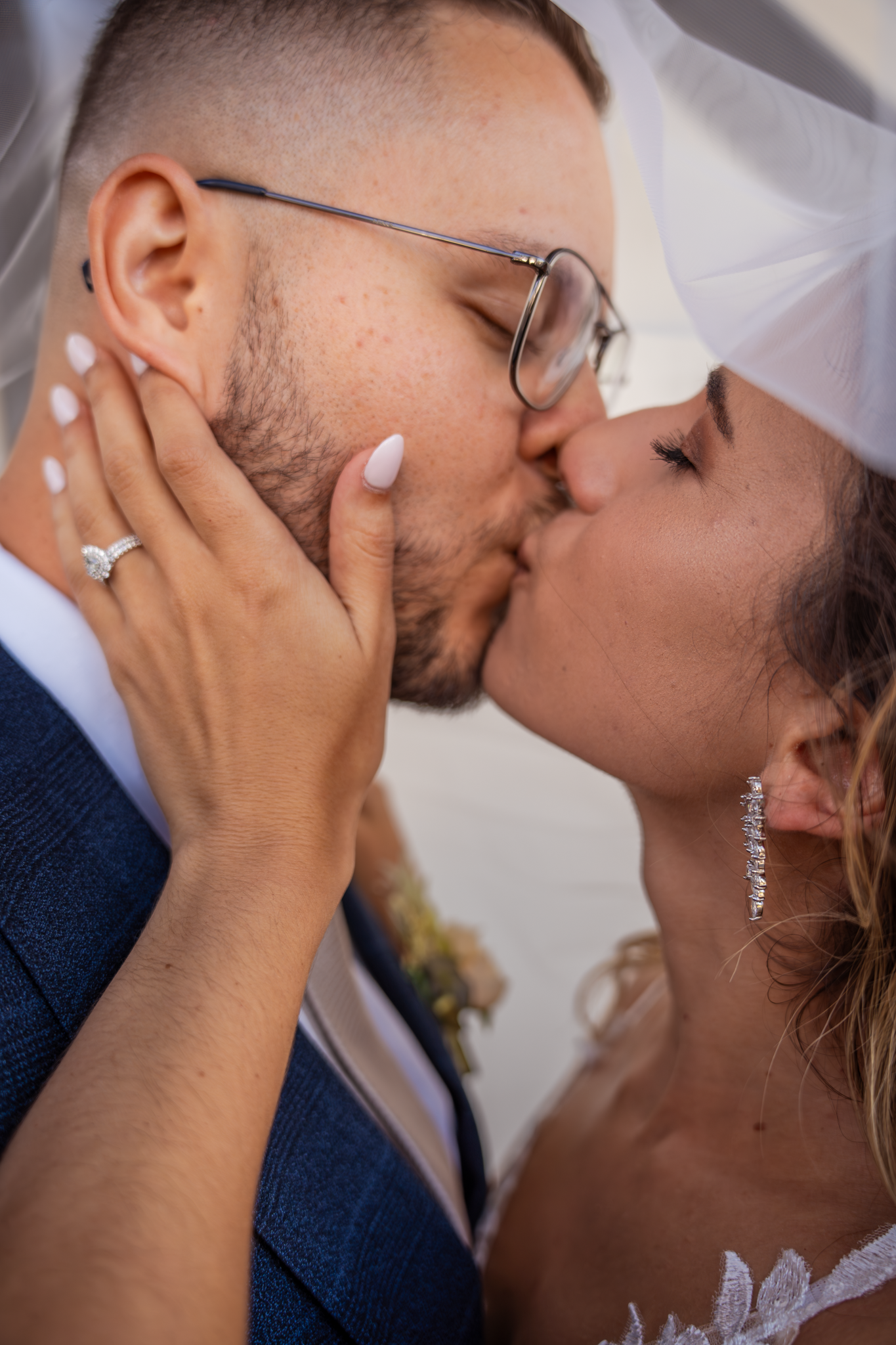 An intimate wedding kiss captured in close-up with delicate lace veil details.