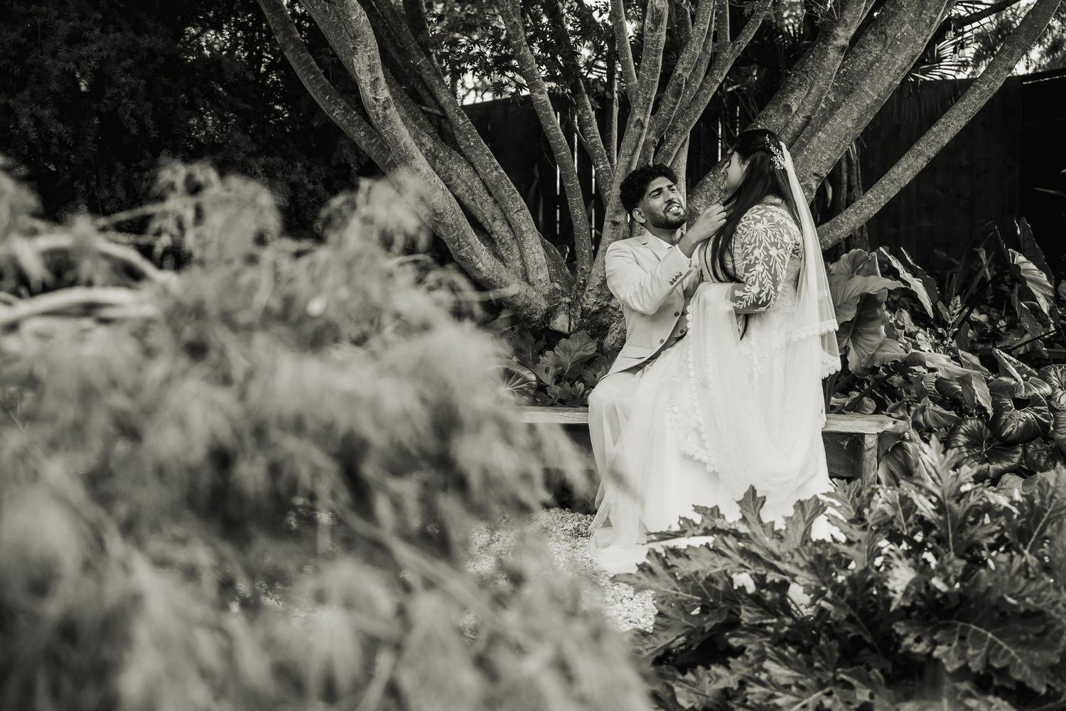 Black and white photo of bride and groom in lush tropical garden setting.