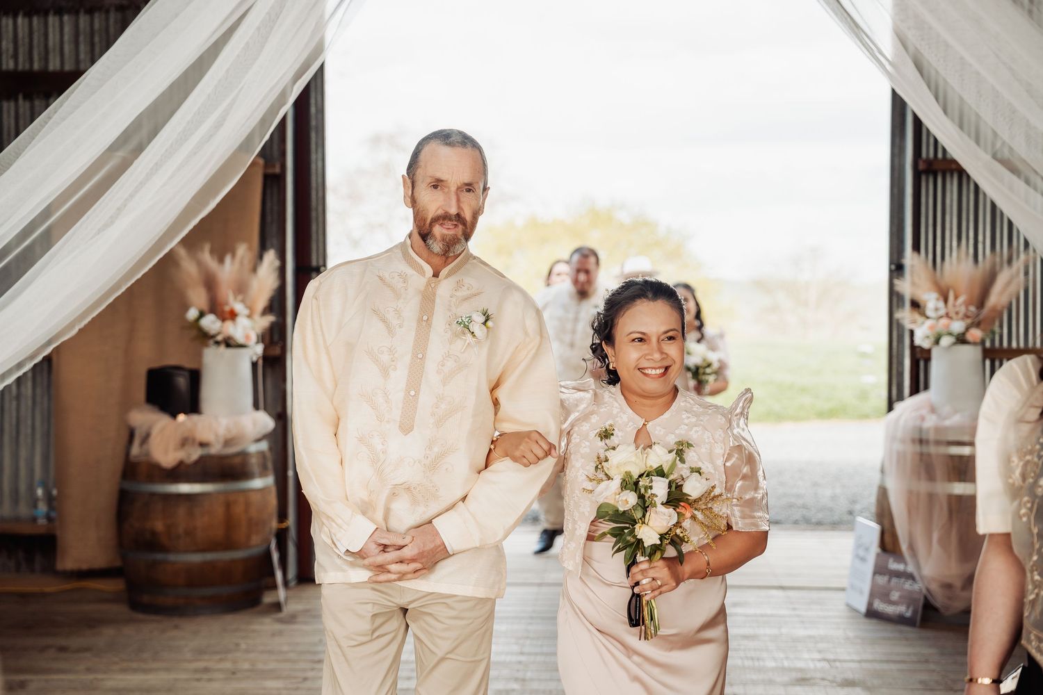 Wedding party members in cream-colored attire gather together during an outdoor celebration.