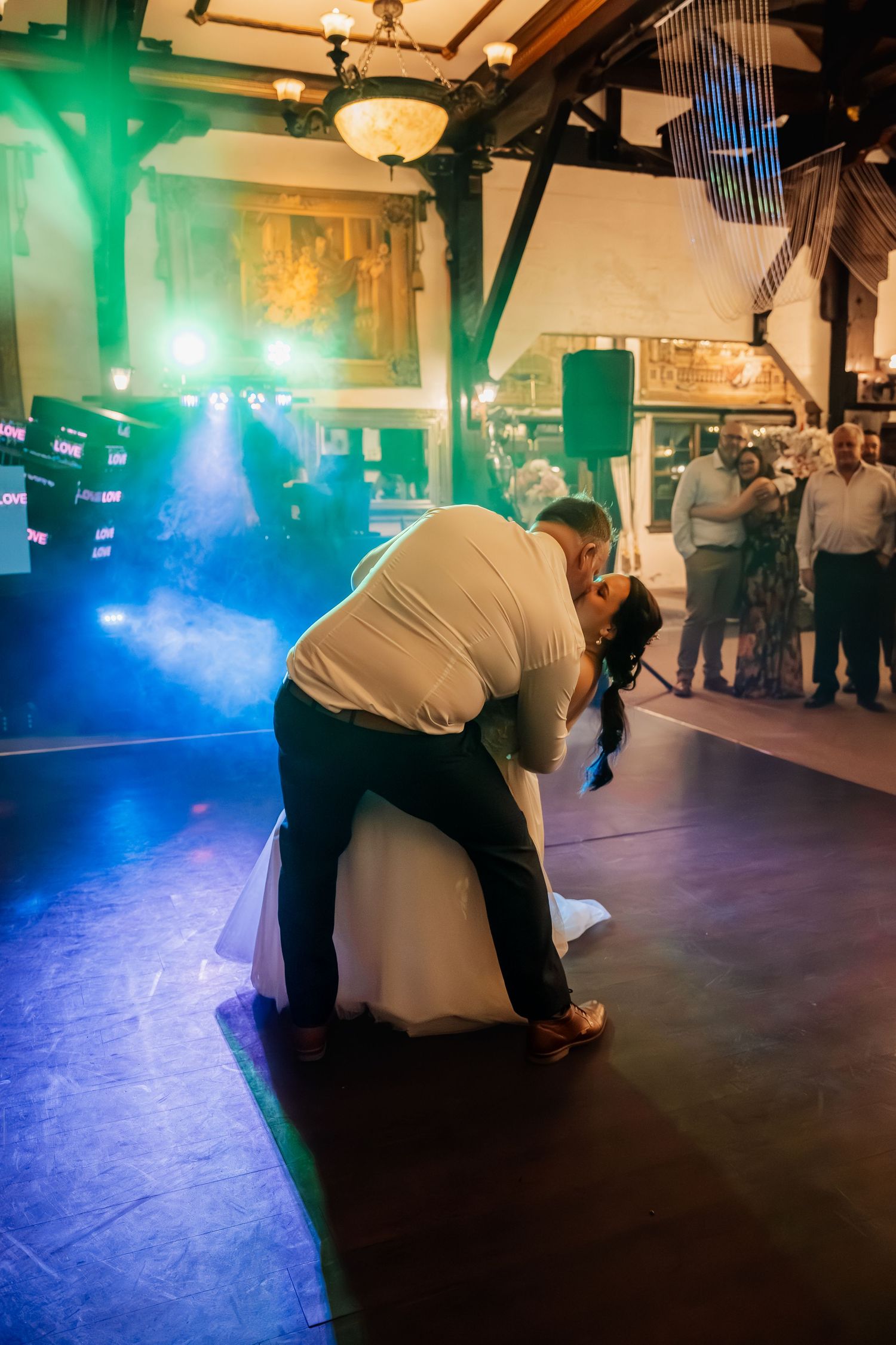 A romantic dip on the dance floor during a wedding reception with blue and green lighting.