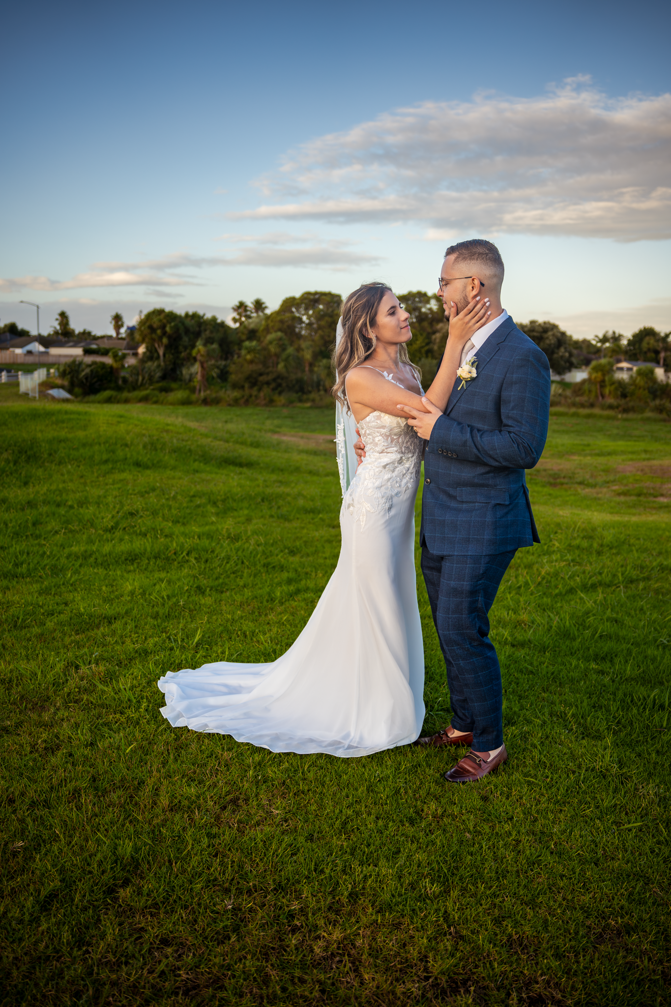 A romantic sunset wedding portrait in an open field with golden light.