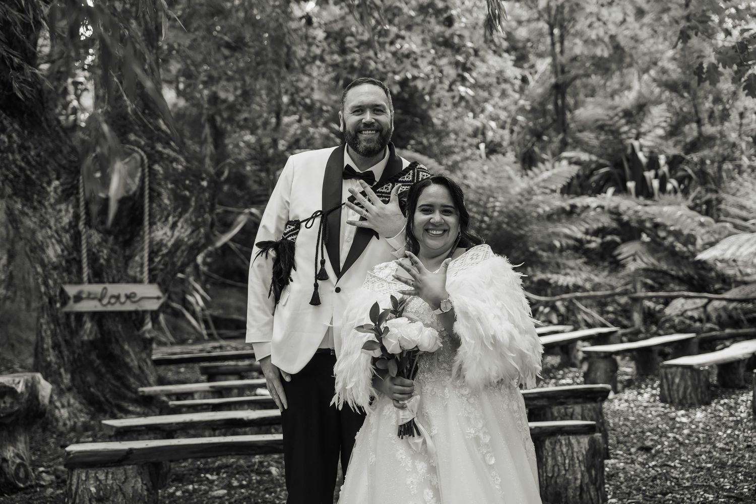 Happy newlyweds pose together in black and white photo at woodland wedding venue.