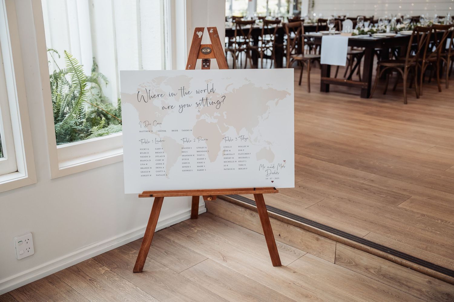 Wedding reception seating chart and decor details displayed on wooden easels in an elegant venue.
