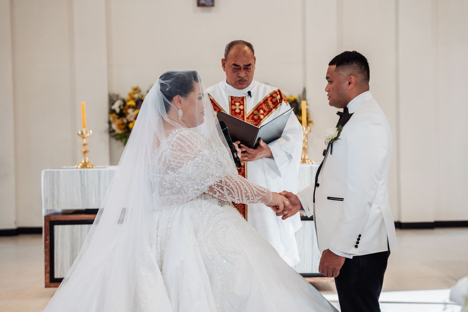 Couple sharing a tender moment on their wedding day in an elegant white wedding dress and white tuxedo.