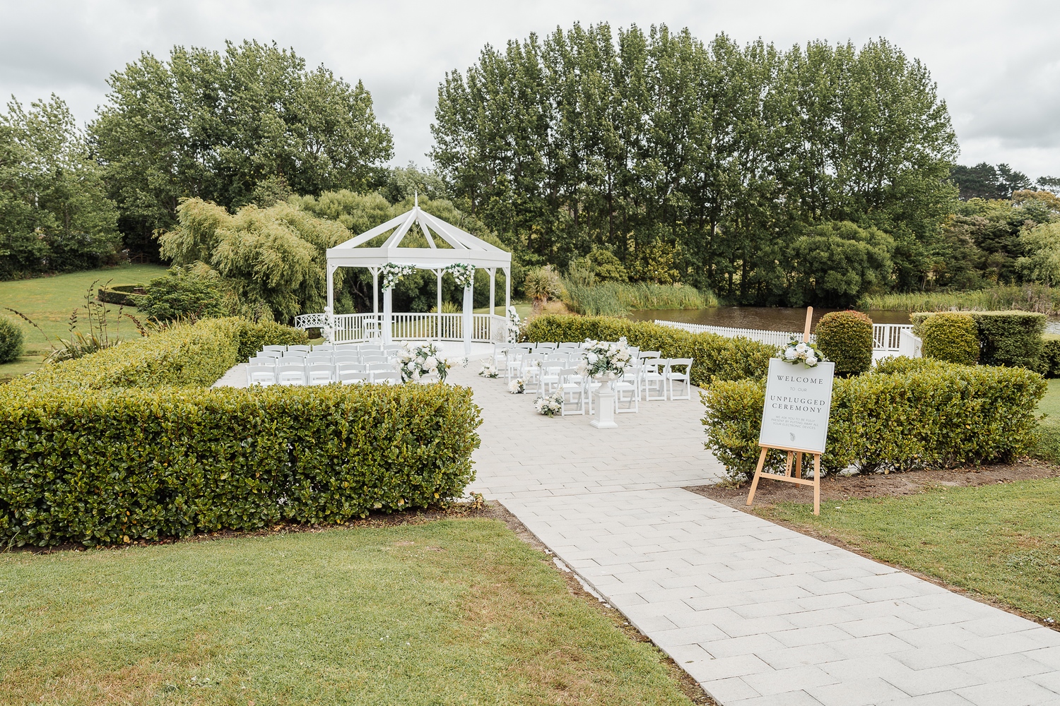 White gazebo and chairs set up for an outdoor garden wedding ceremony.