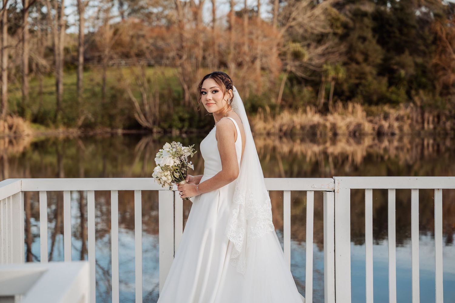White deck railing overlooking a scenic lake with autumn trees in the background.