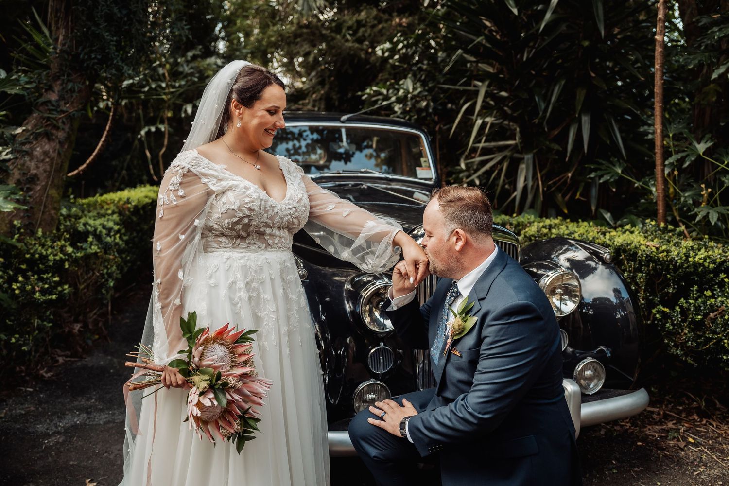 Romantic garden wedding ceremony with couple walking along a lush tree-lined path.