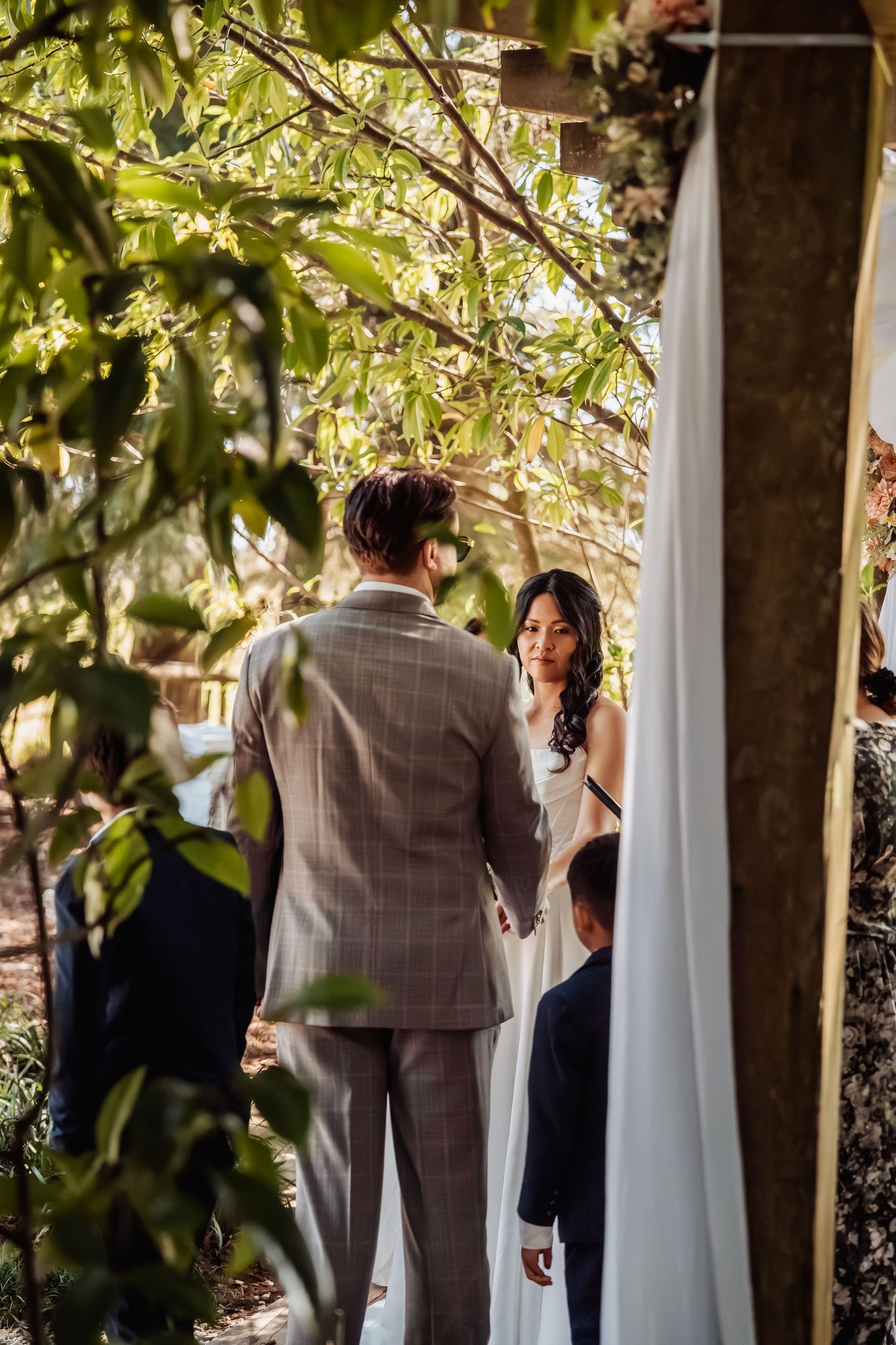 Bride and groom exchange vows under a lush garden arbor during an intimate outdoor wedding ceremony.