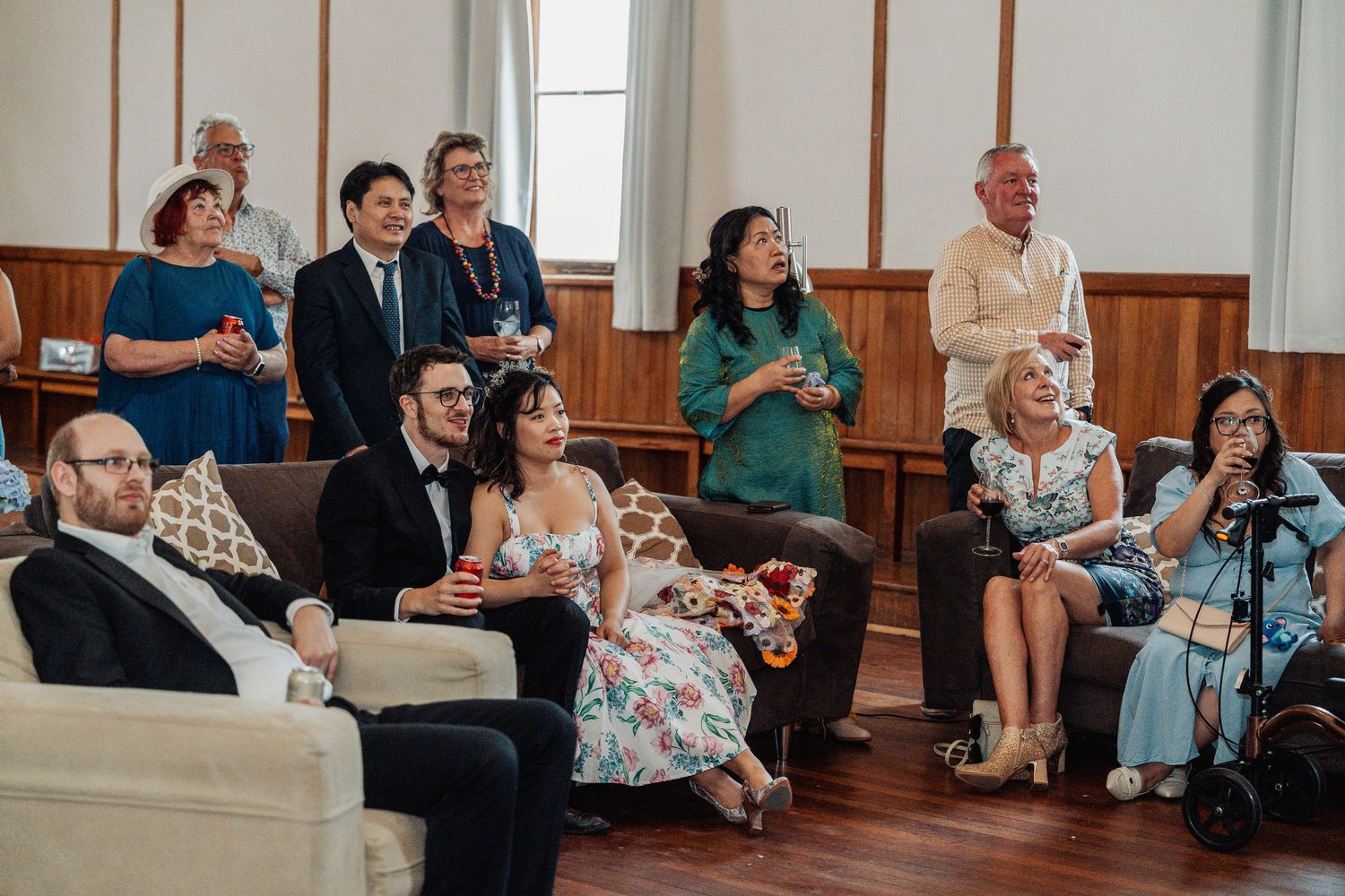 Wedding guests gathered in a wood-paneled room watching and celebrating during the reception.