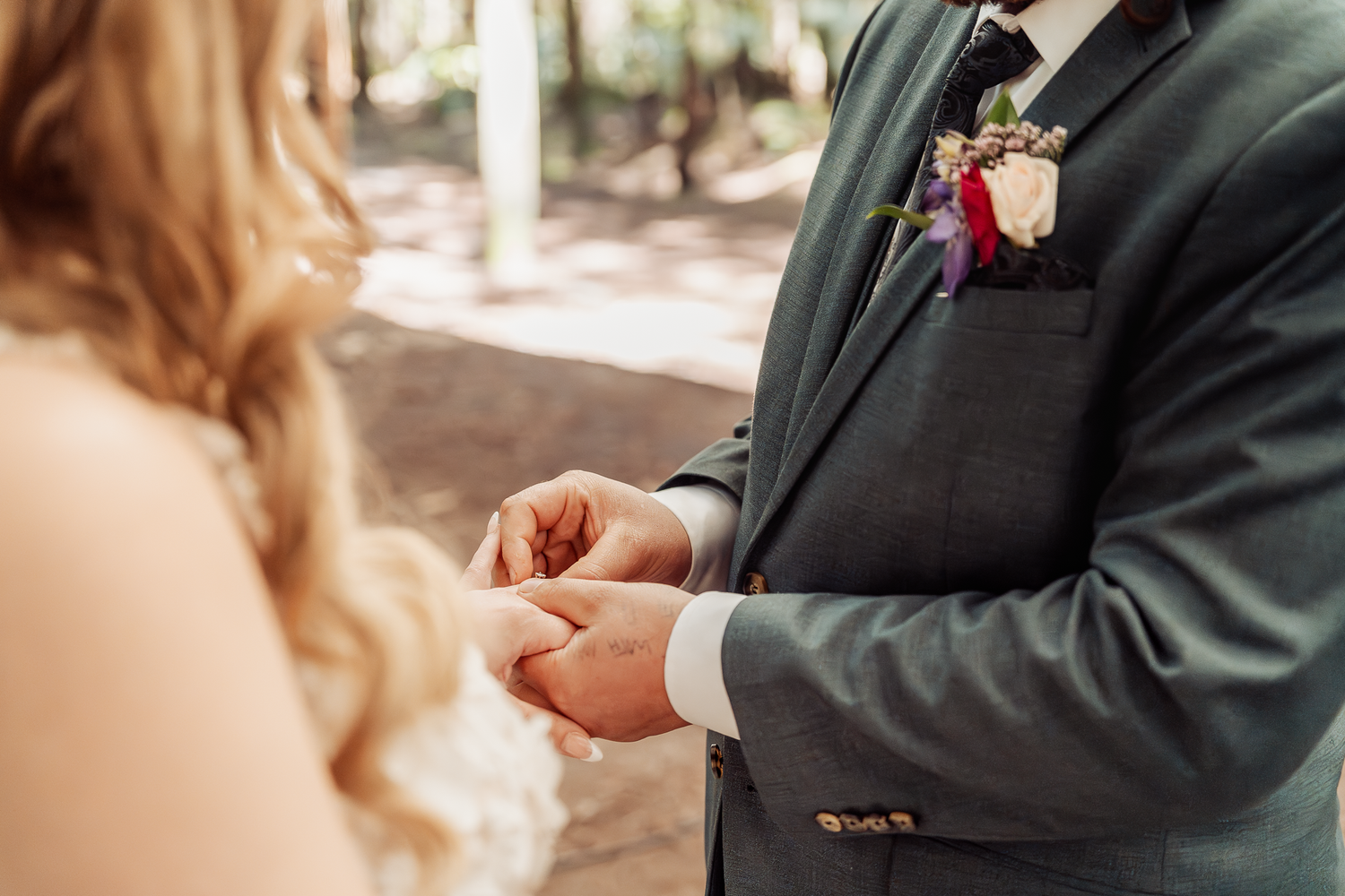 Close-up of hands exchanging wedding rings during ceremony.