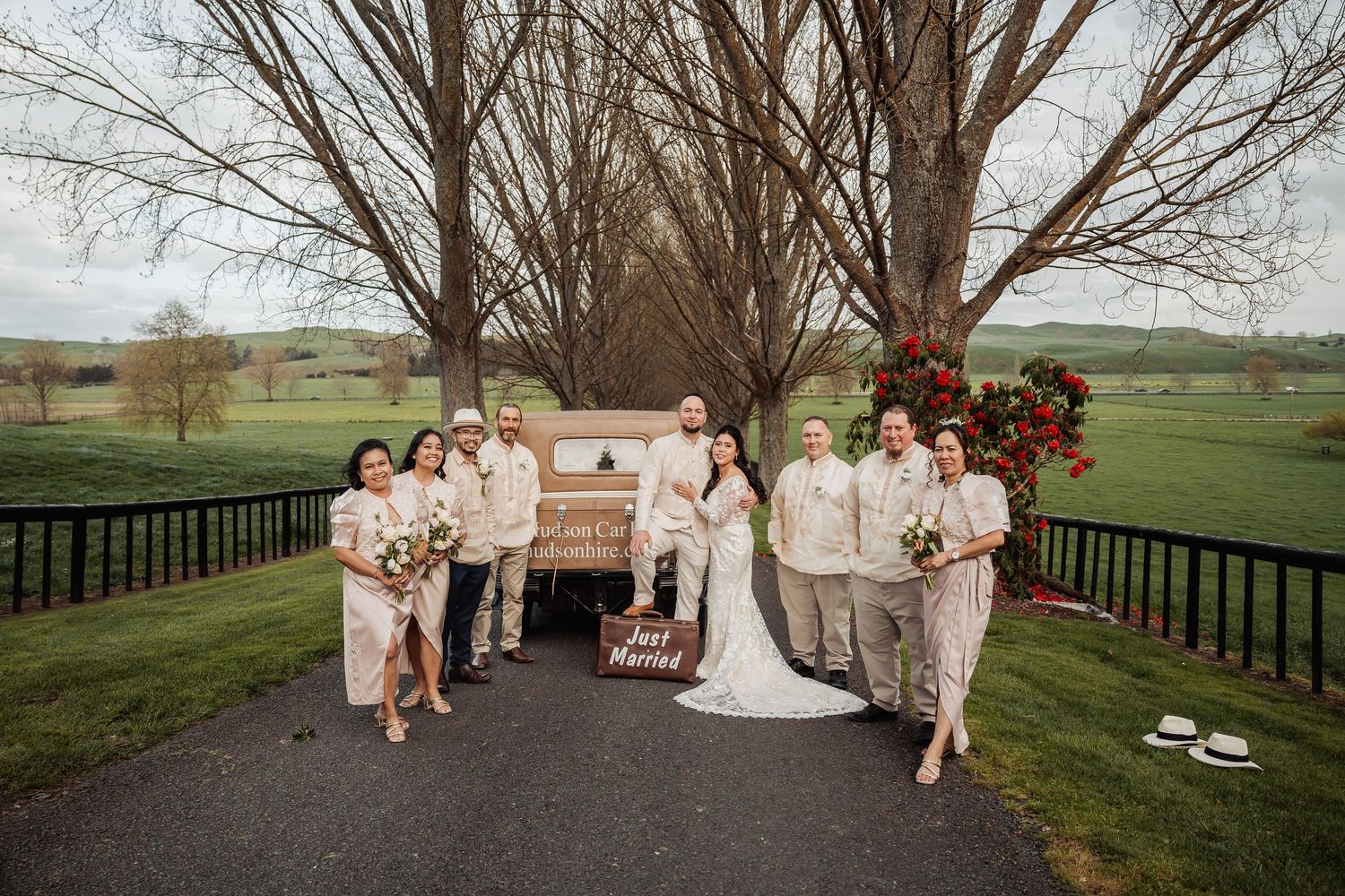 Wedding party poses on a tree-lined path with vintage couch and floral arrangements.