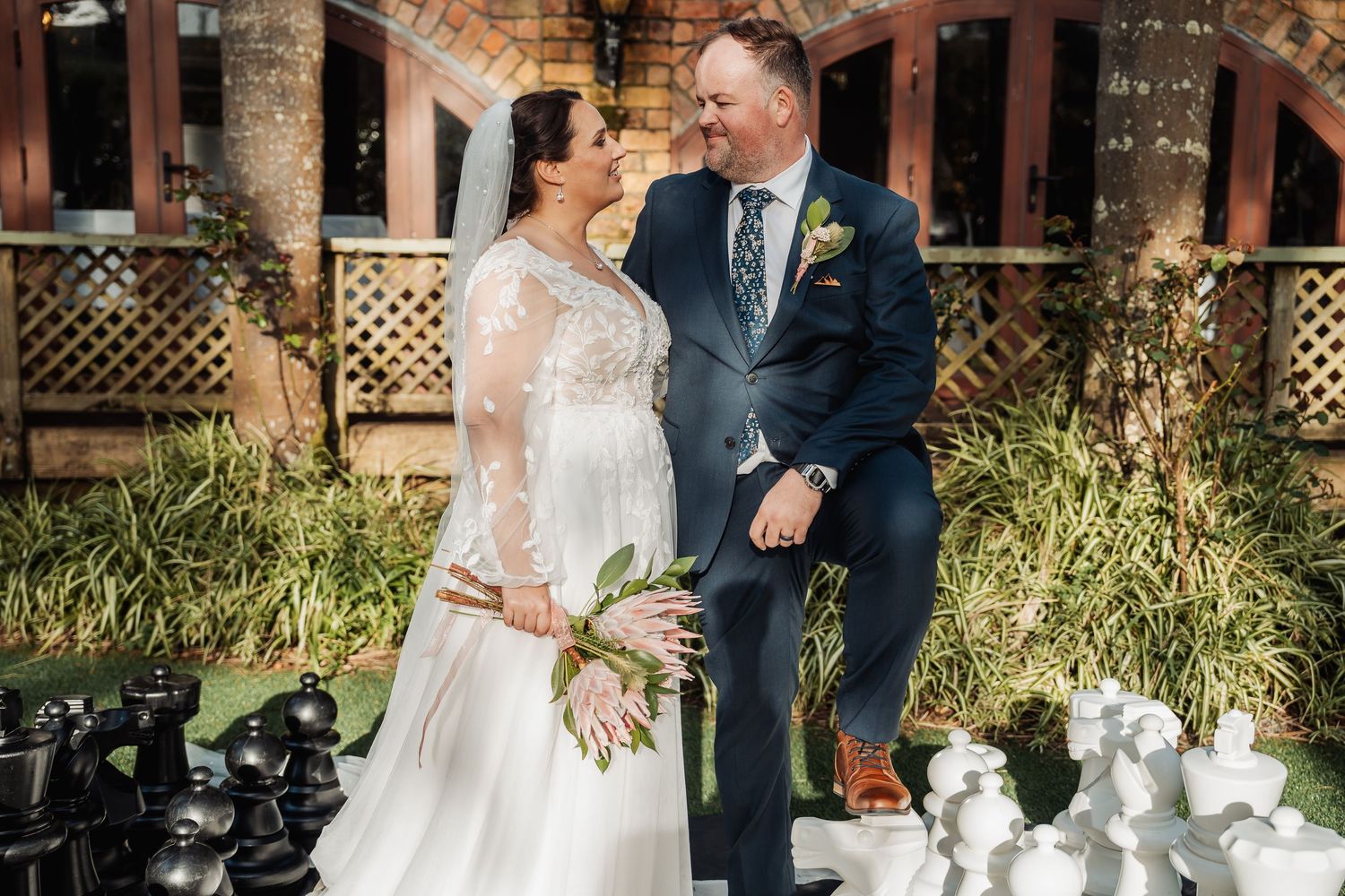 Outdoor wedding celebration with elegant decor featuring brick columns and natural garden surroundings.