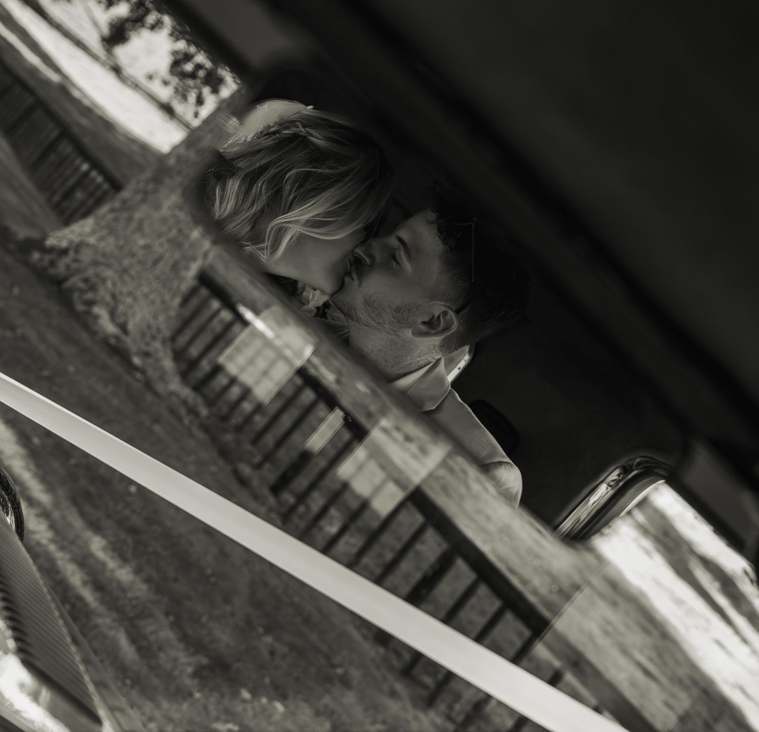 Black and white portrait of a woman leaning on a railing with soft natural light.