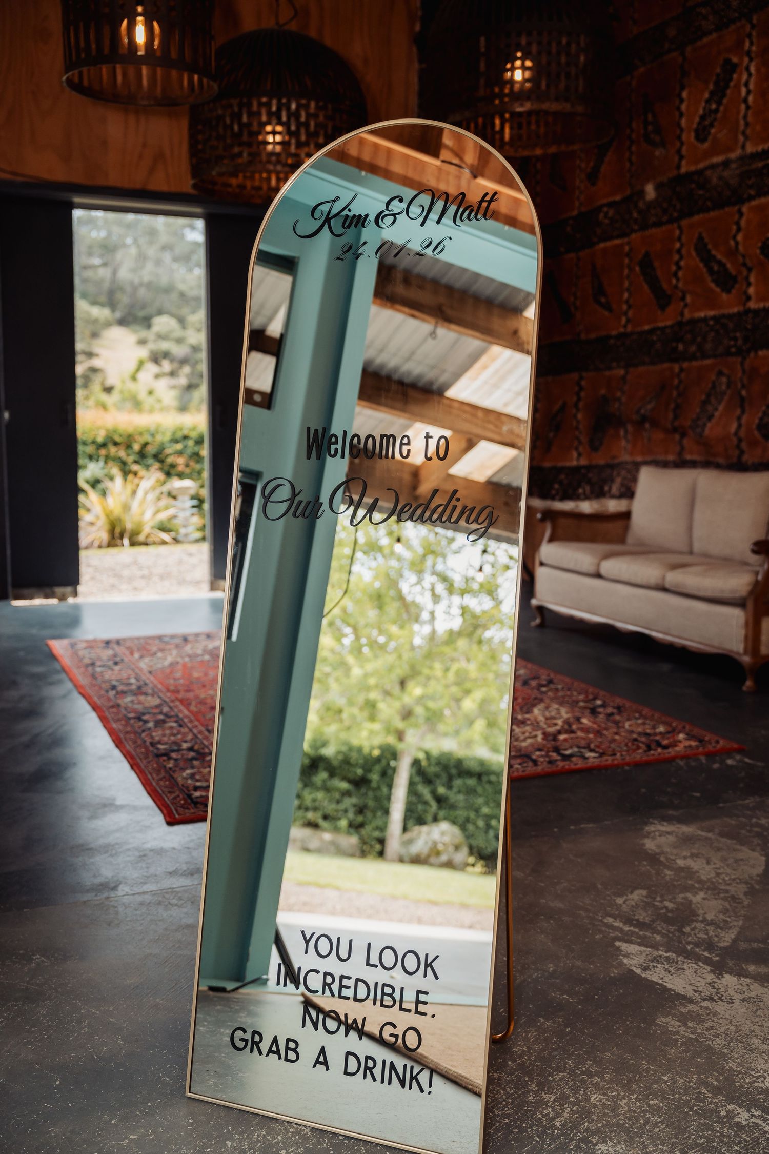 Elegant wedding welcome mirror sign reading Kim and Matt with You Look Incredible Now Go Grab a Drink.